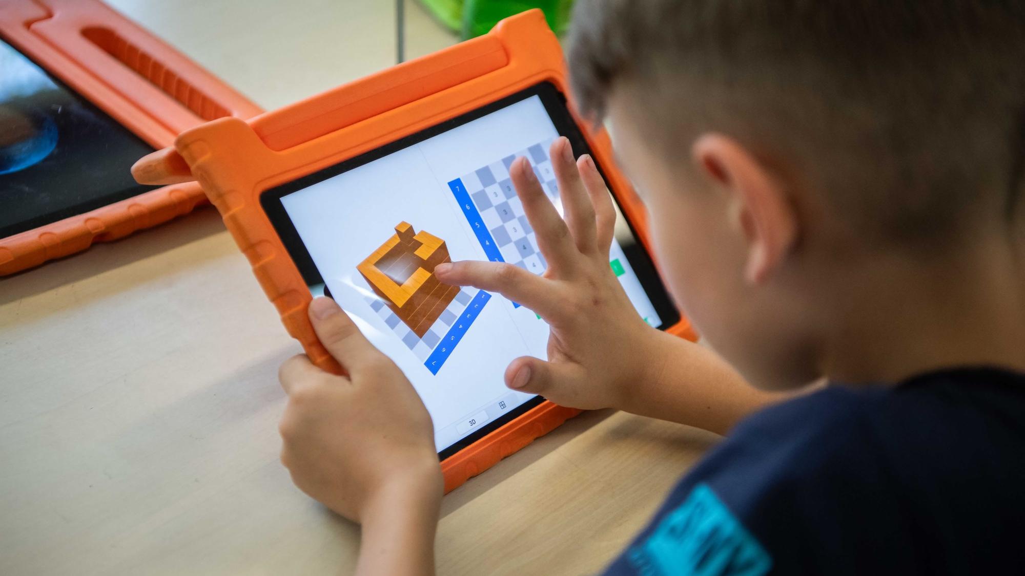 Das Bild zeigt einen Grundschüler, der an einem Tablet arbeitet.