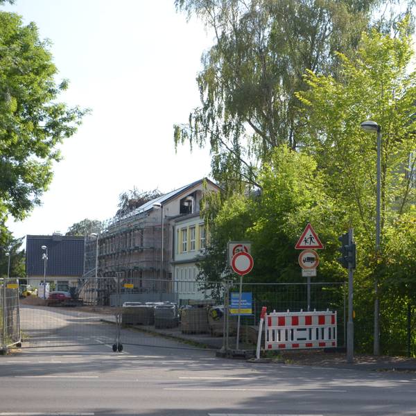Die Straße ist mit einem Bauzaun abgesperrt. Im Hintergrund liegen die Gebäude der Franziskusschule.