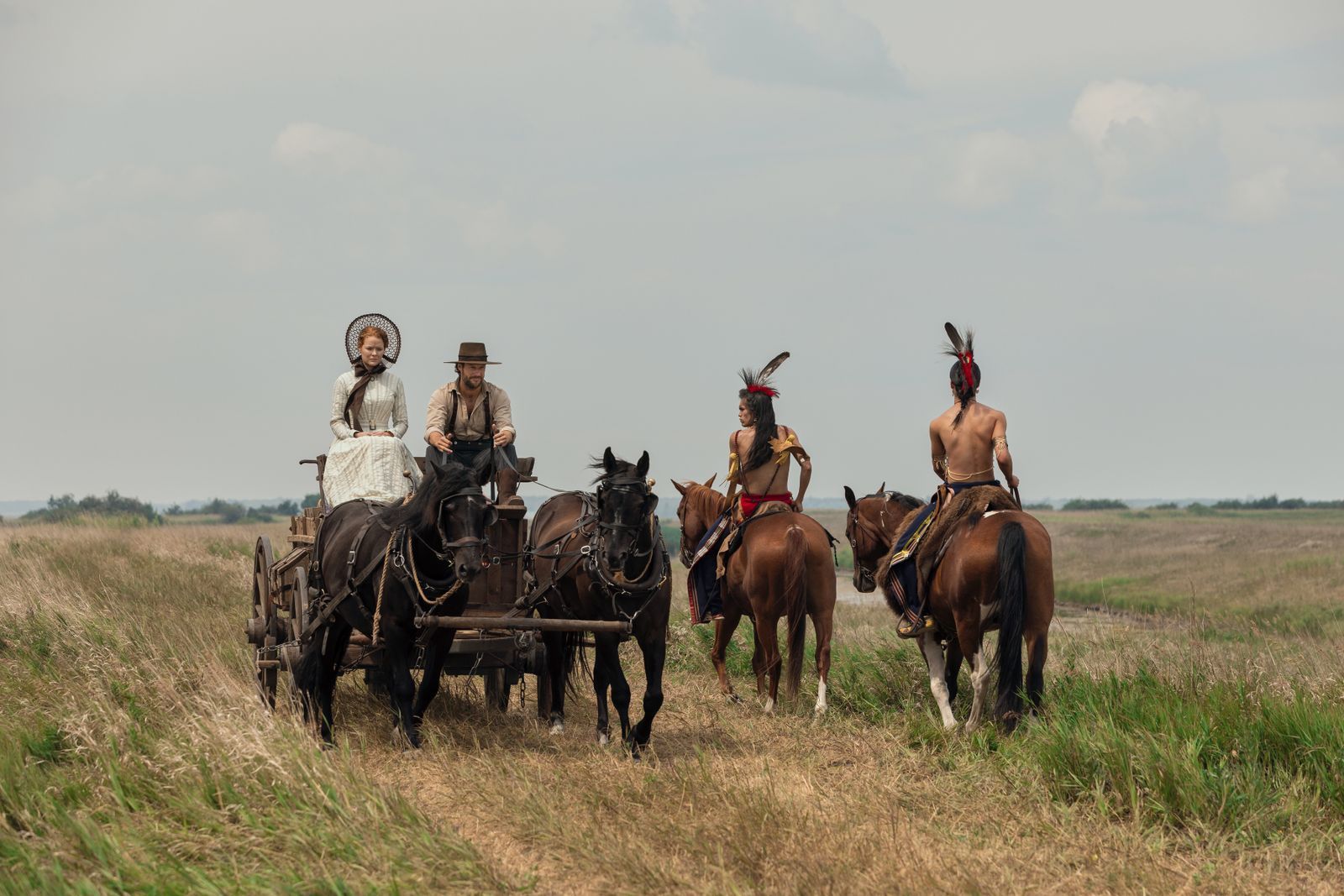 An Begegnungen mit Indigenen müssen sich Caroline (Crosby Fitzgerald) und Charles (Luke Bracey, zweiter von rechts) noch gewöhnen. Kansas war zur Zeit ihrer Ankunft „Indianerland“.  
 (Bild: Eric Zachanowich/Netflix © 2026)