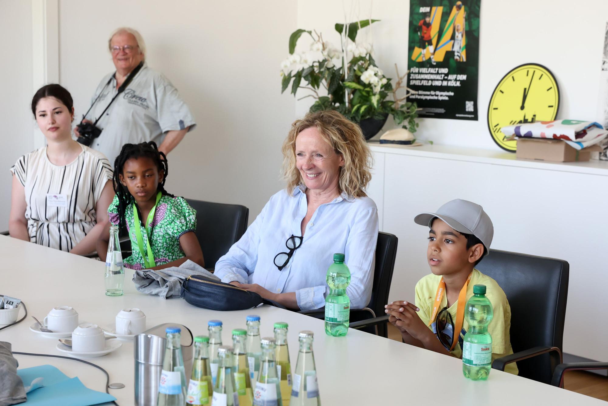 Die Herausgeberin und stellv. Vereinsviorsitzende Isabella Neven DuMont sitzt mit zwei Mädchen und einem Jungen vom Kinderrat des Linoclubs in Lindweiler am Konferenztisch im Historischen Rathaus zu Köln.