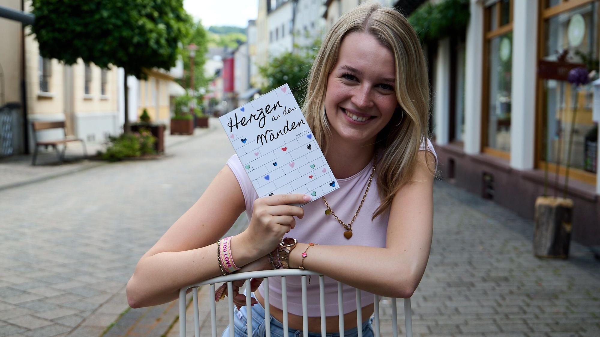 Maja Hölz steht in der Fußgängerzone und hält ihr Buch in den Händen.