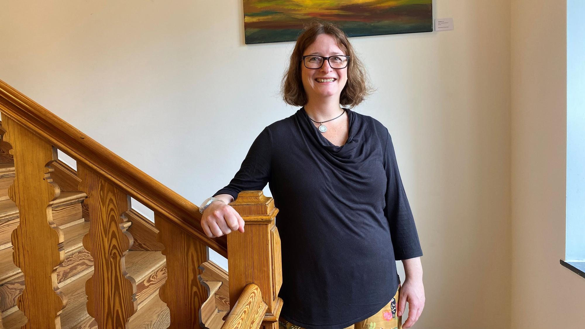 Eine Frau steht an einer hölzernen Treppe.