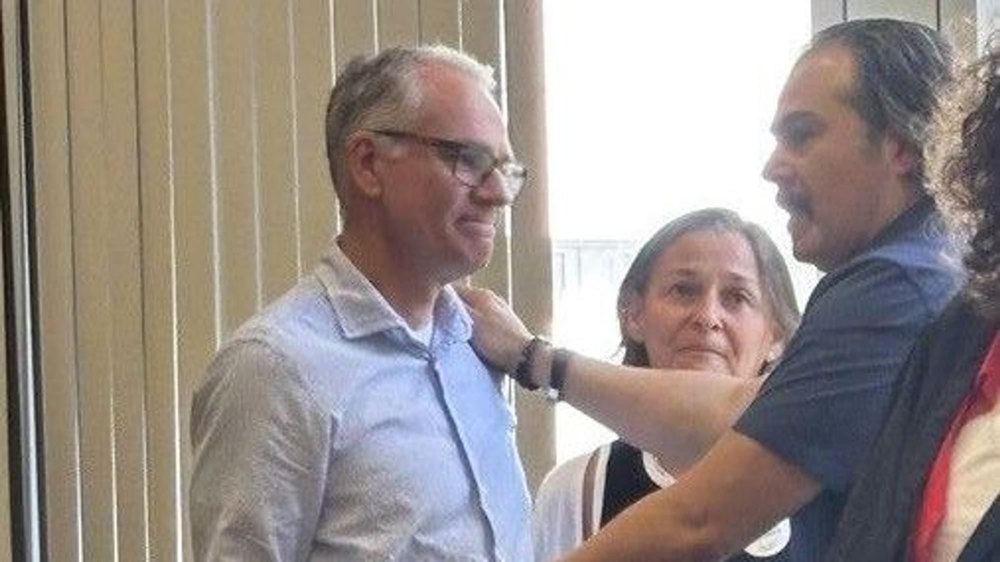 Auf dem Bild sind die Eltern von Luis Paulo und der Vater von Avin zu sehen, die sich umarmen.