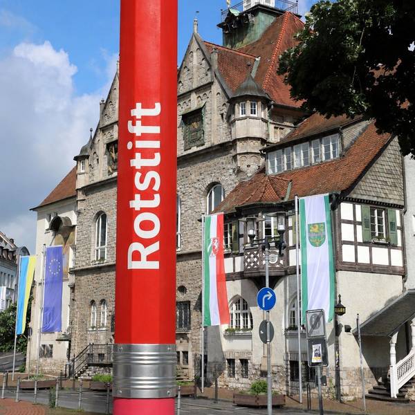 Die Fotomatage zeigt einen roten Stift vor dem Rathaus.