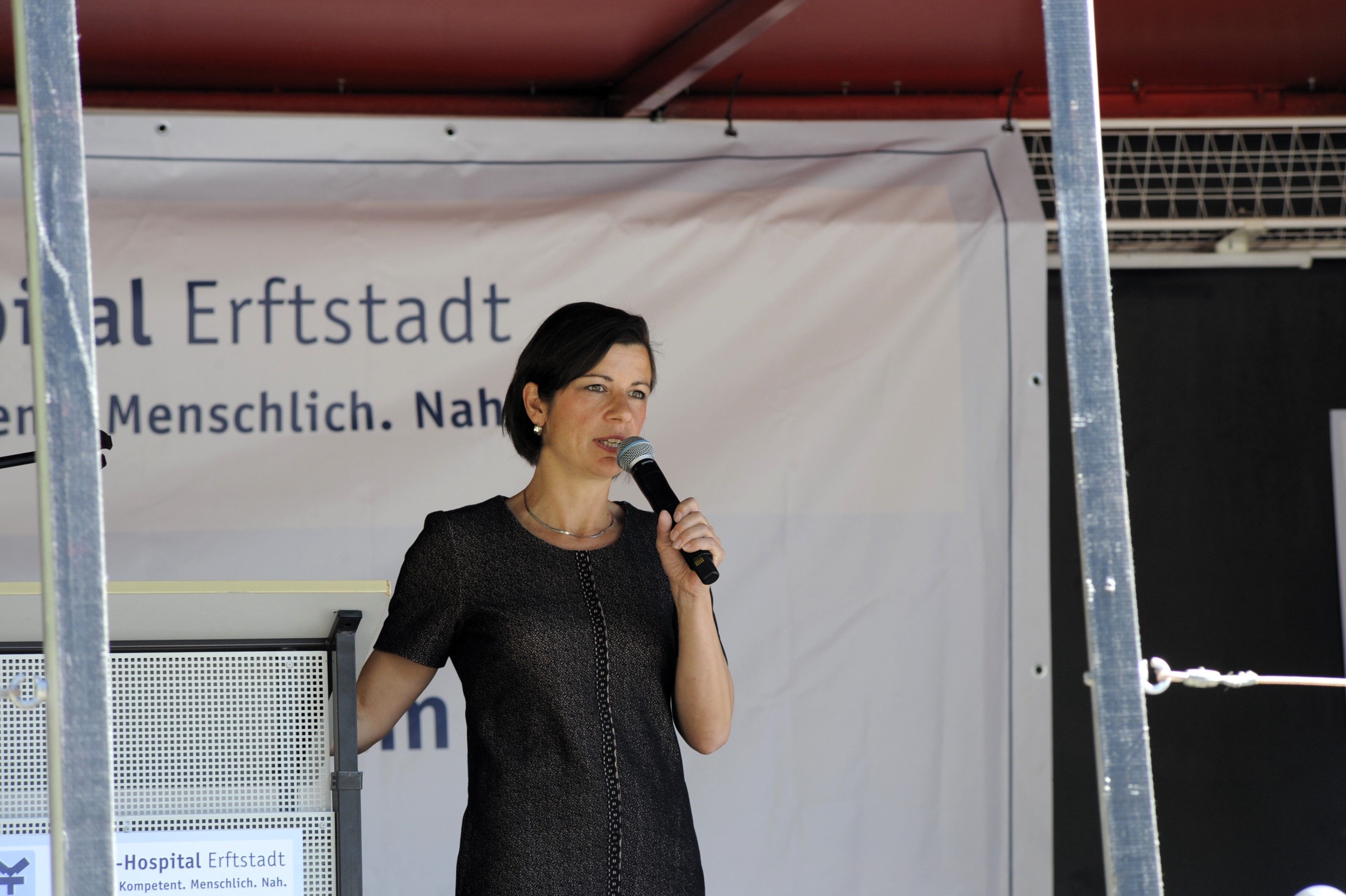 Eine Frau spricht auf einer Bühne in ein Mikrofon.