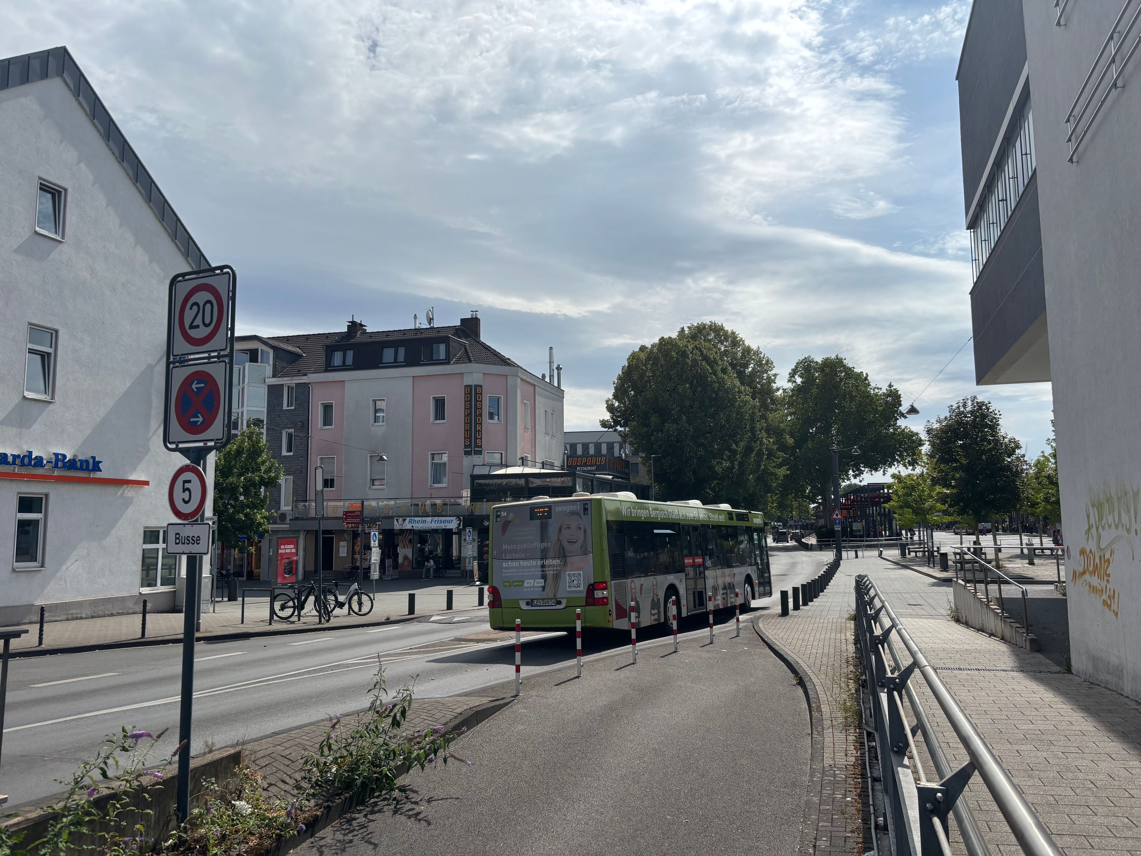 Ein Linienbus fährt auf einer breiten Straße Richtung Busbahnhof.