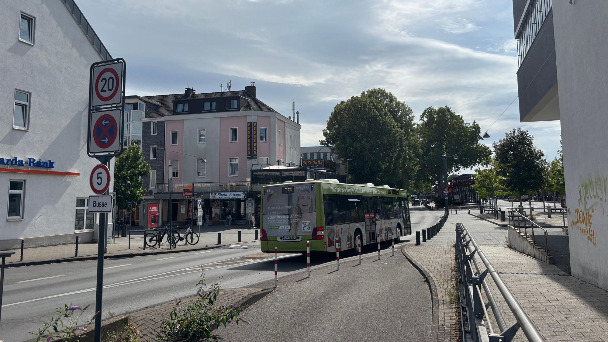 Ein Linienbus fährt auf einer breiten Straße Richtung Busbahnhof.
