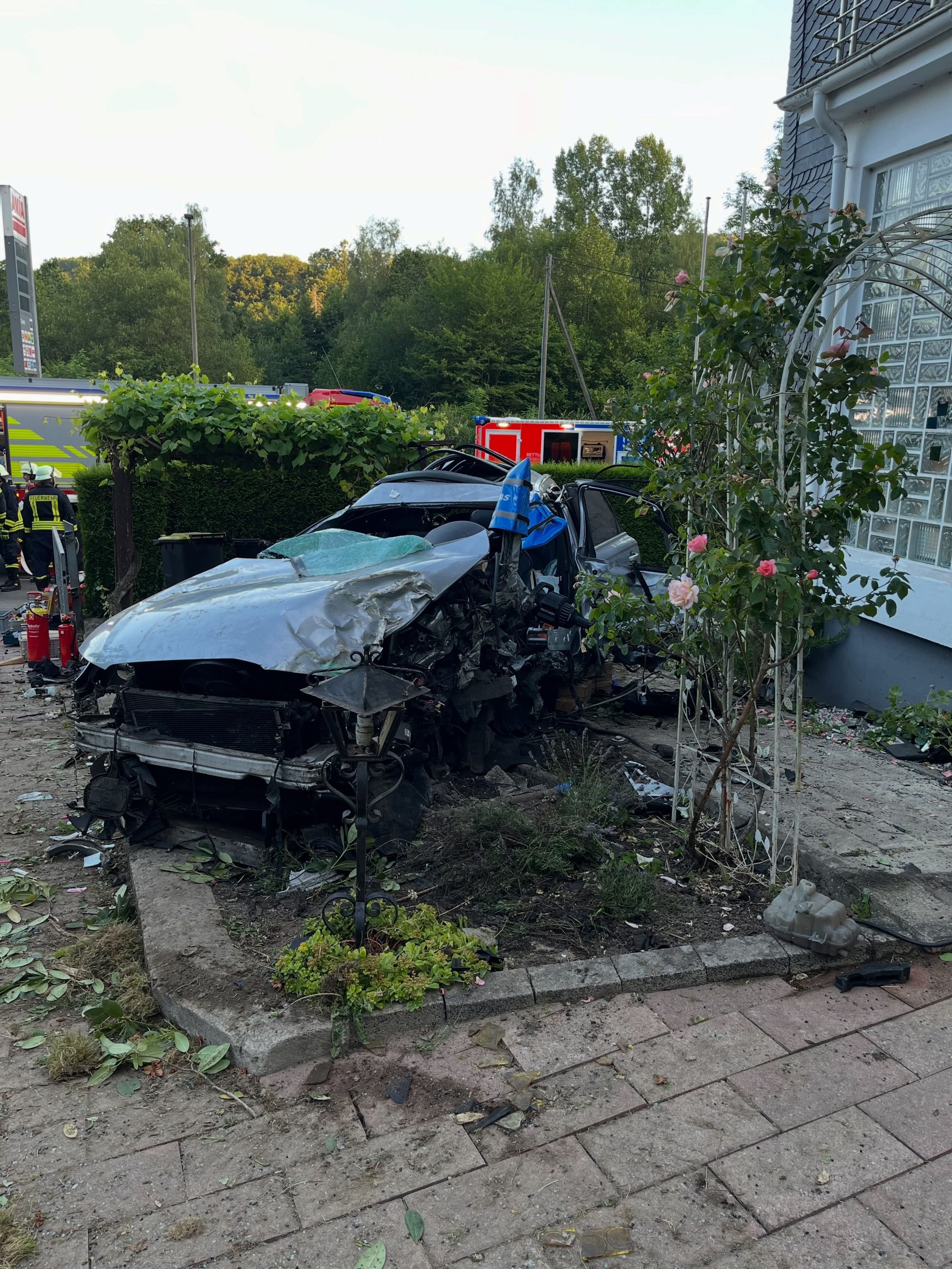 Ein kaputtes Auto in einem Vorgarten.