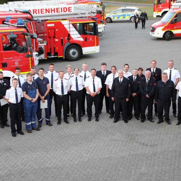 Ein Gruppenbild vor Feuerwehrfahrzeugen.