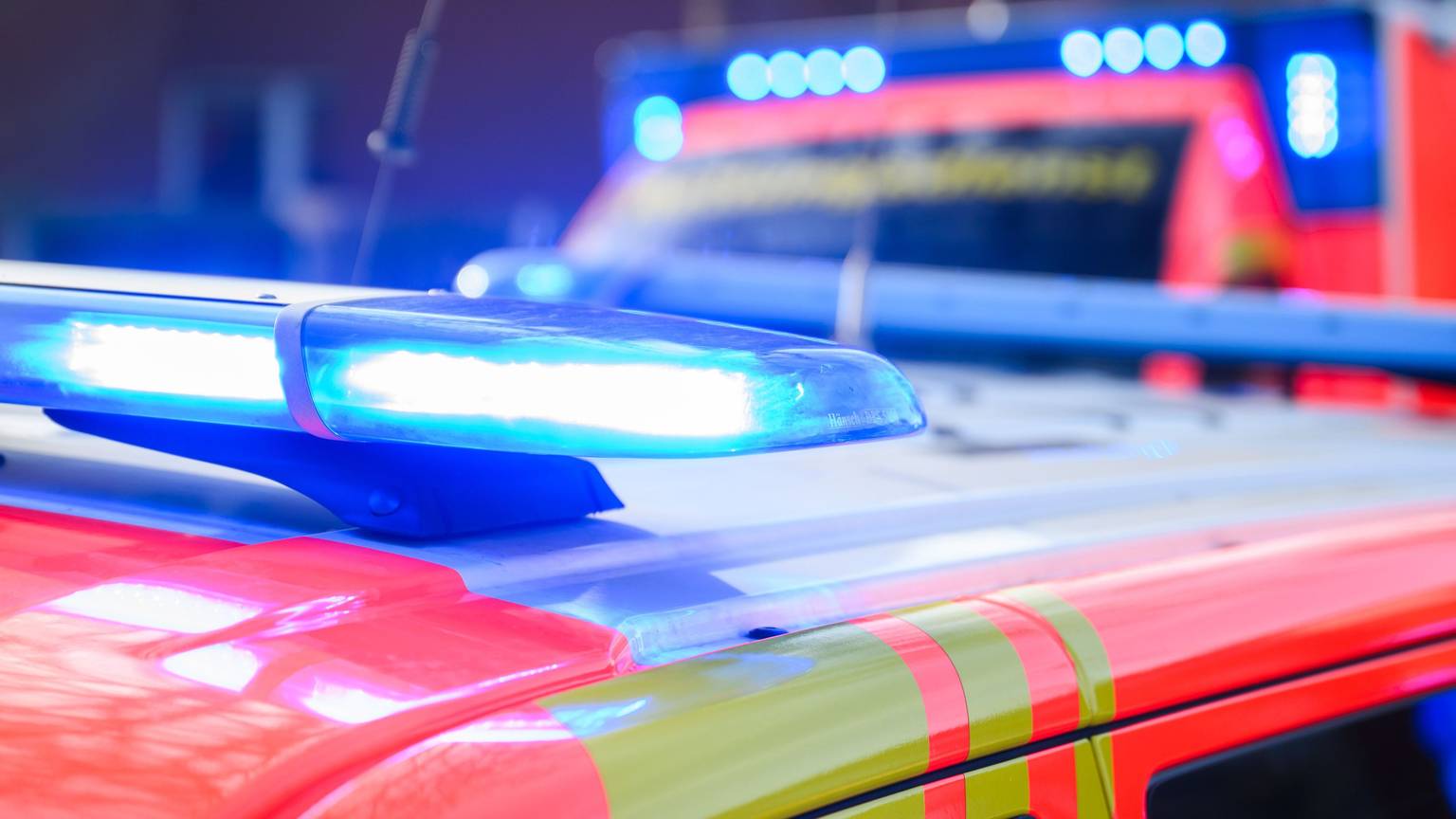 Blaulichter leuchten an einer Einsatzstelle auf einem Notarztfahrzeug und einem Rettungswagen.