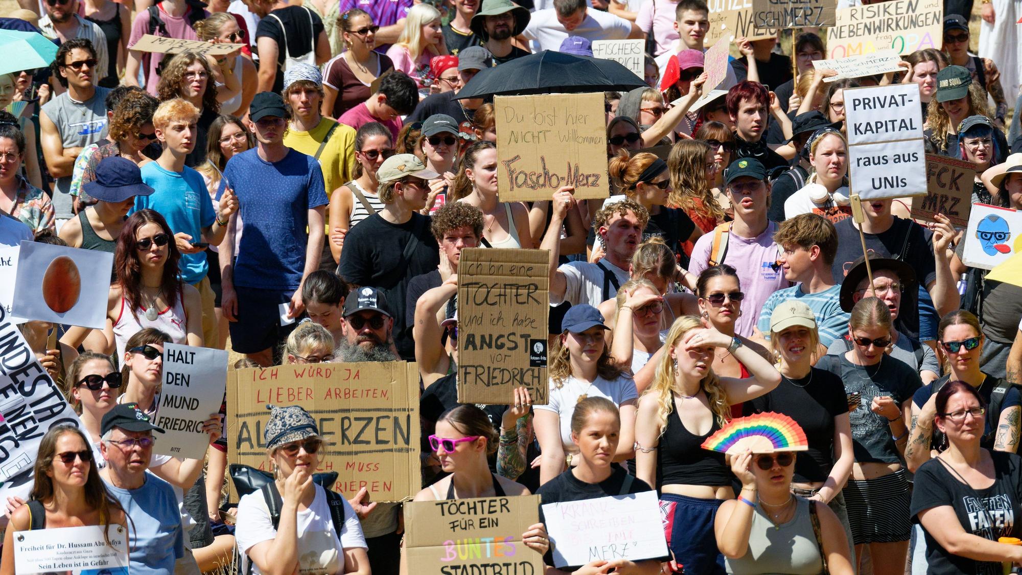 Mehrere Hundert Menschen protestieren vor der Universität in Köln, während Bundeskanzler Merz (CDU) bei der Eröffnung der Adenauer School of Government redet.