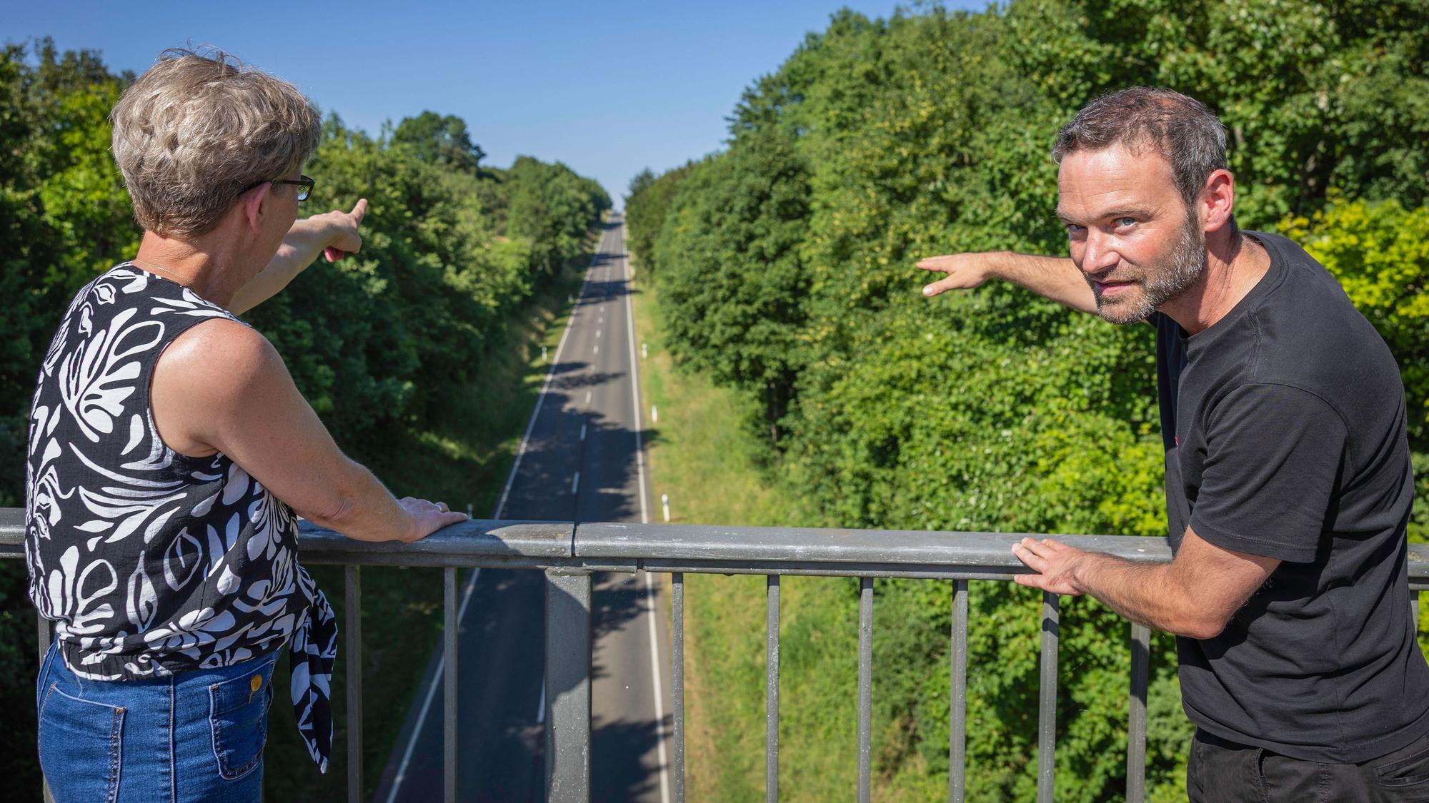 Schmitz und Mandl blicken von einer Brücke auf die den Berg hinabführende L206.