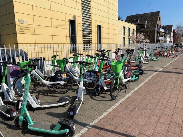 An der Aachener Straße blockieren wild abgestellte E-Scooter den Gehweg komplett.
