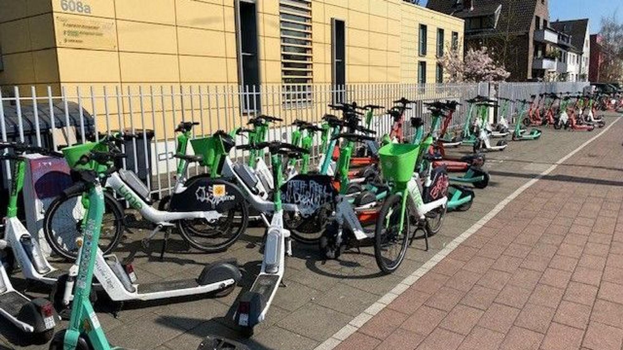 An der Aachener Straße blockieren wild abgestellte E-Scooter den Gehweg komplett.
