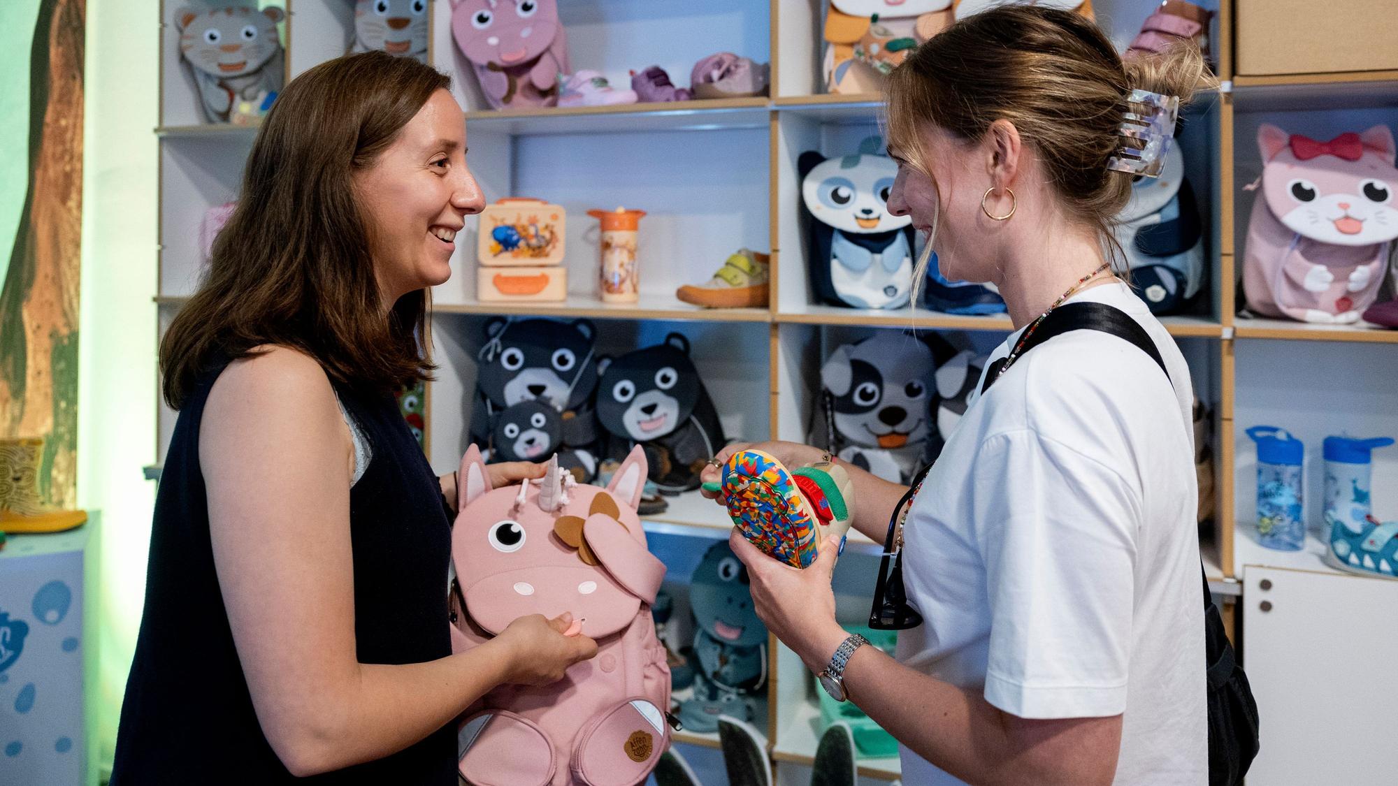 Zwei Frauen unterhalten sich in einem Laden über Fond-of-Produkte, die in ihren Händen und in den Regalen zu sehen sind.
