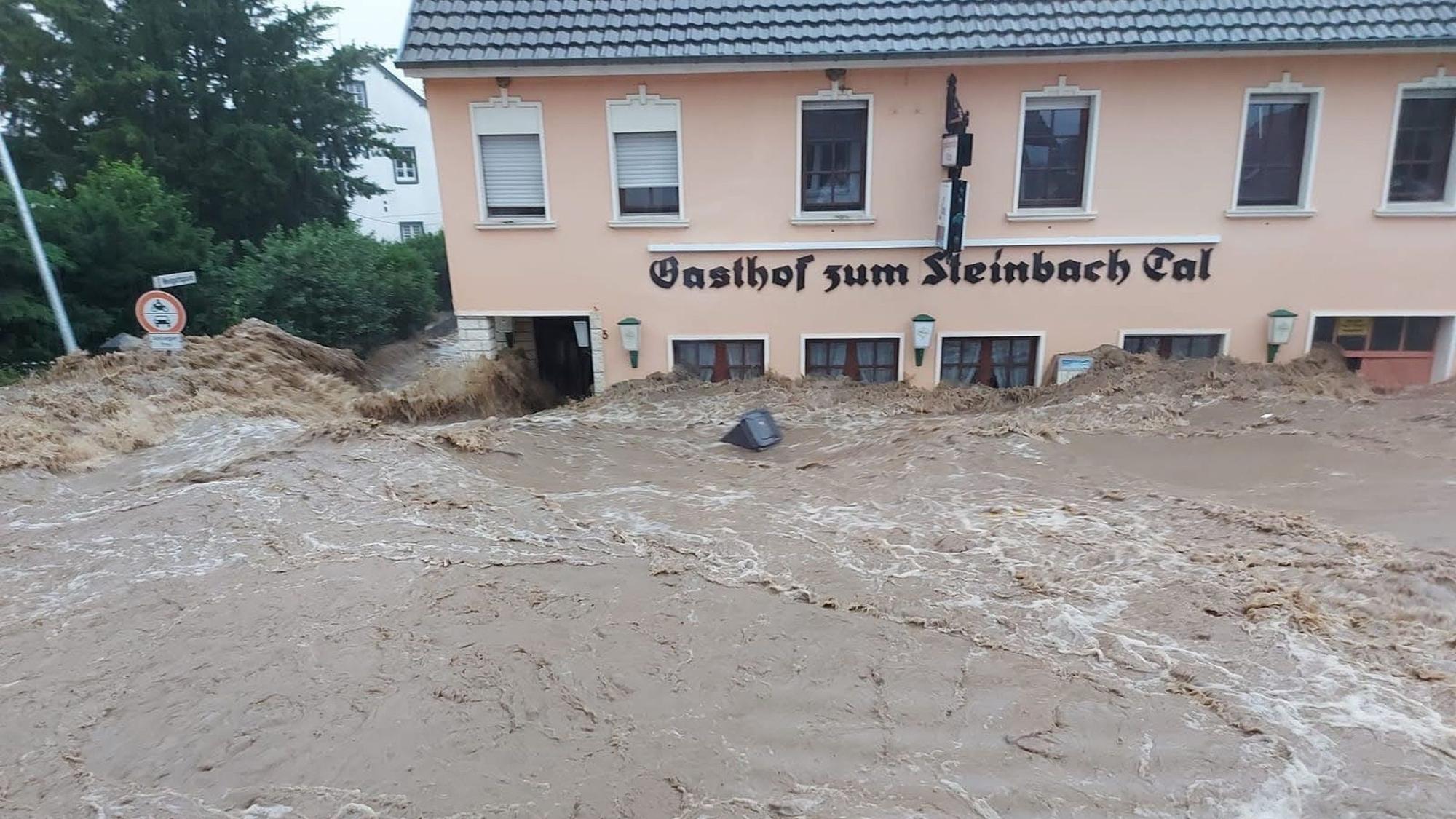 Das Hochwasser fließt an einer Gaststätte entlang, der Pegel erreicht fast die Oberkante der Fenster im Erdgeschoss.
