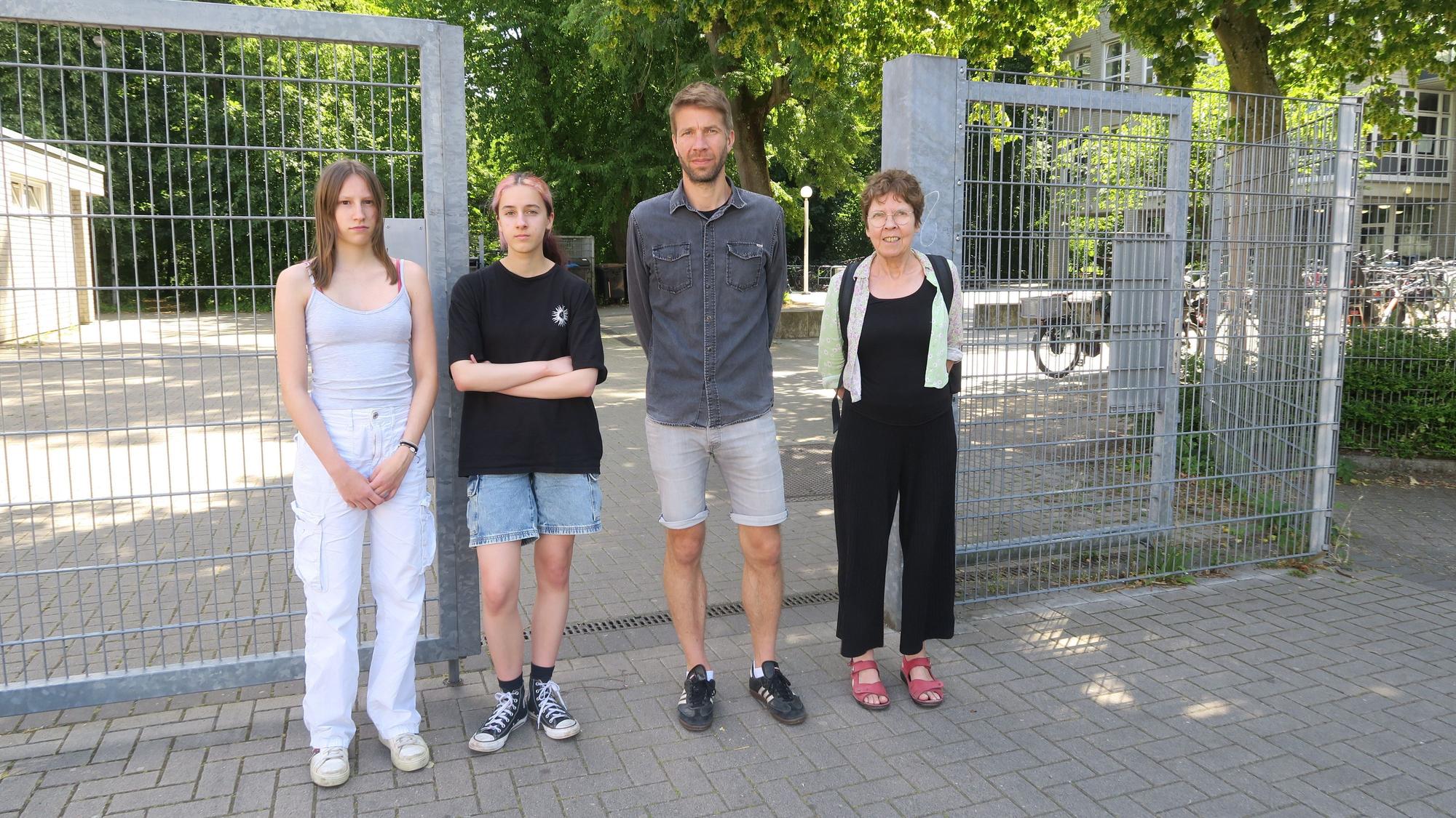 Zwei Schülerinnen, ein Lehrer und eine Lehrerin stehen vor dem offenen Schultor der Gesamtschule in Bocklemünd.
