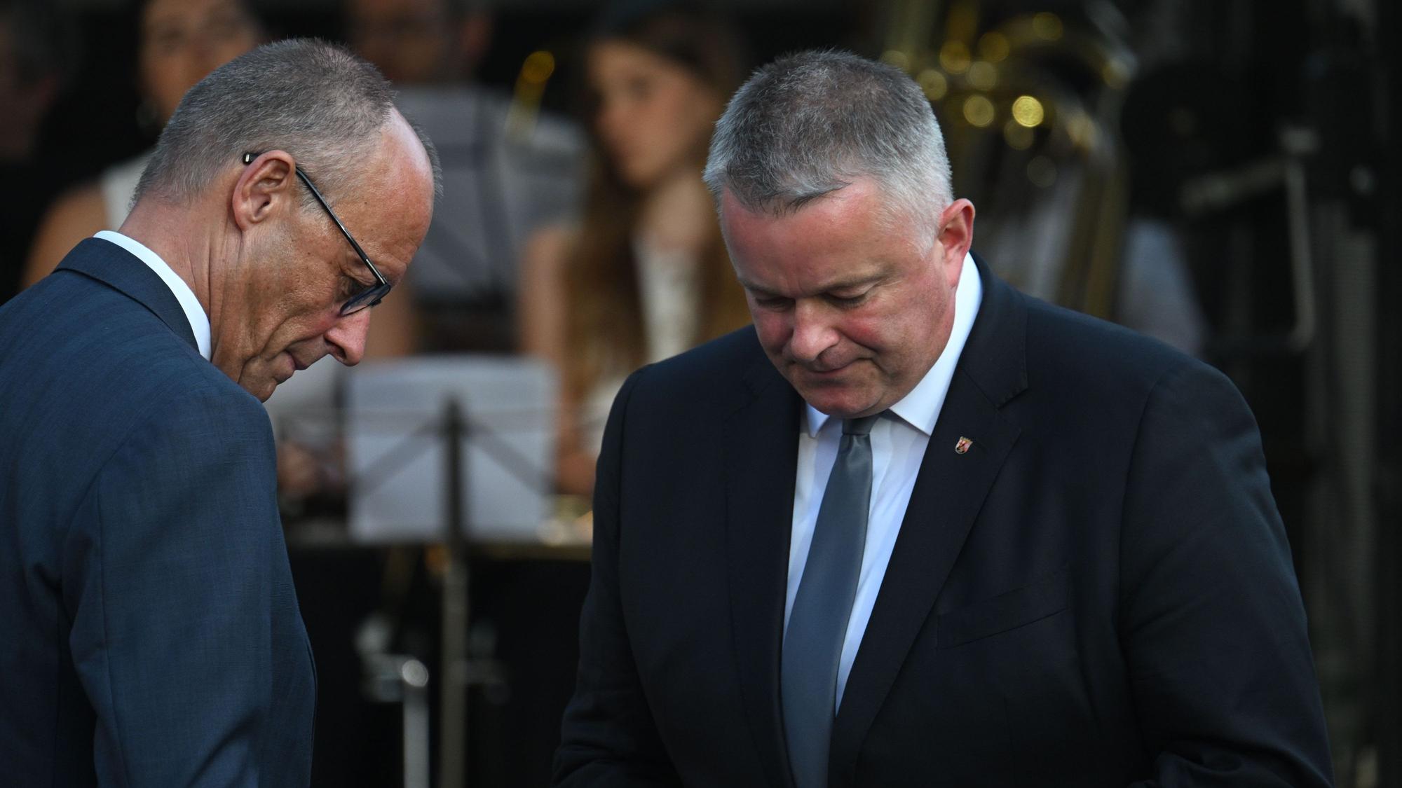 Gordon Schnieder (CDU, r), Ministerpräsident von Rheinland-Pfalz, und Bundeskanzler Friedrich Merz (CDU) stehen am Rande der zentralen Gedenkveranstaltung zum fünften Jahrestag der Flutkatastrophe im Ahrtal auf dem Marktplatz nebeneinander.