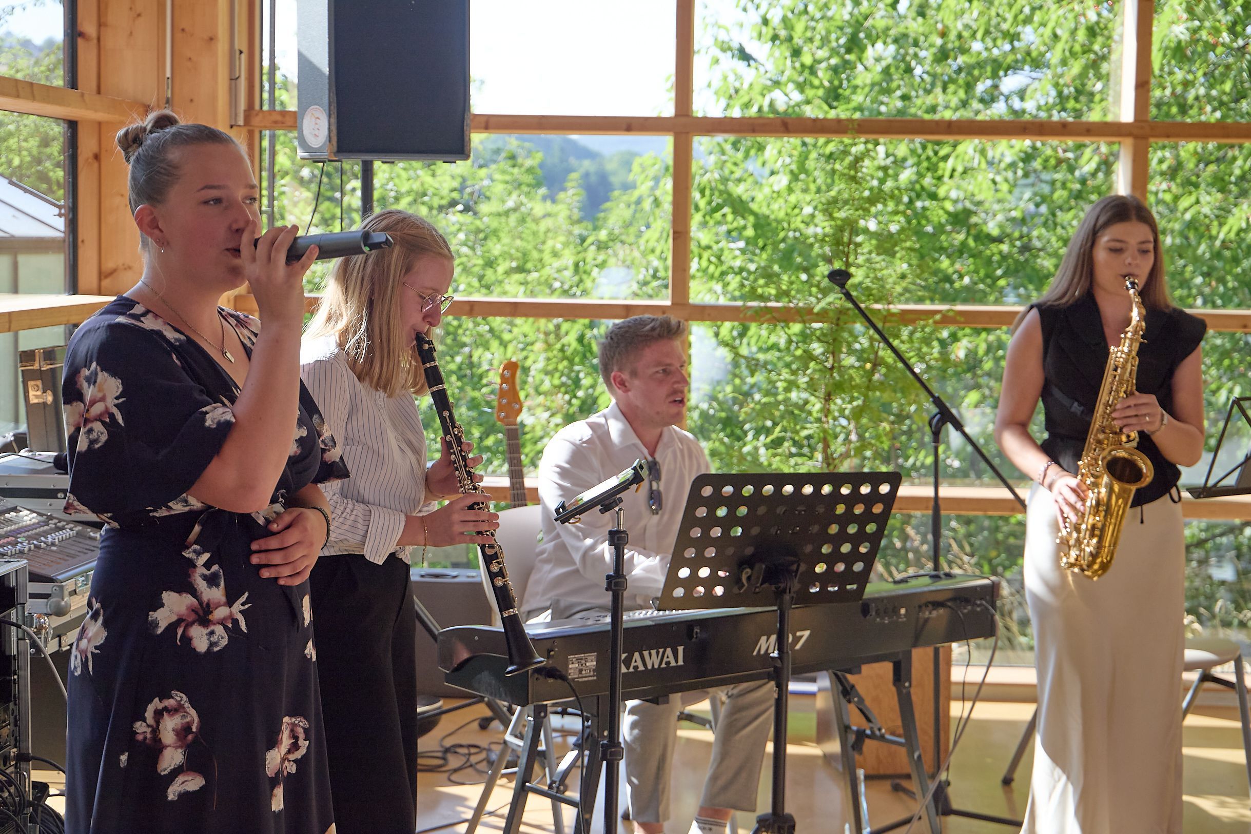 Eine Schülerin singt, zwei weitere und ihr Lehrer spielen Instrumente.