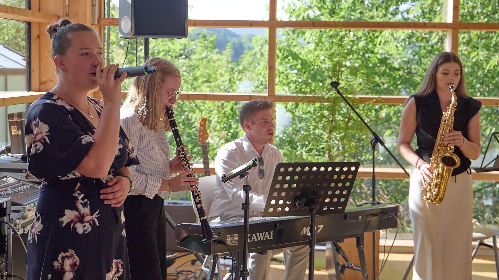 Eine Schülerin singt, zwei weitere und ihr Lehrer spielen Instrumente.
