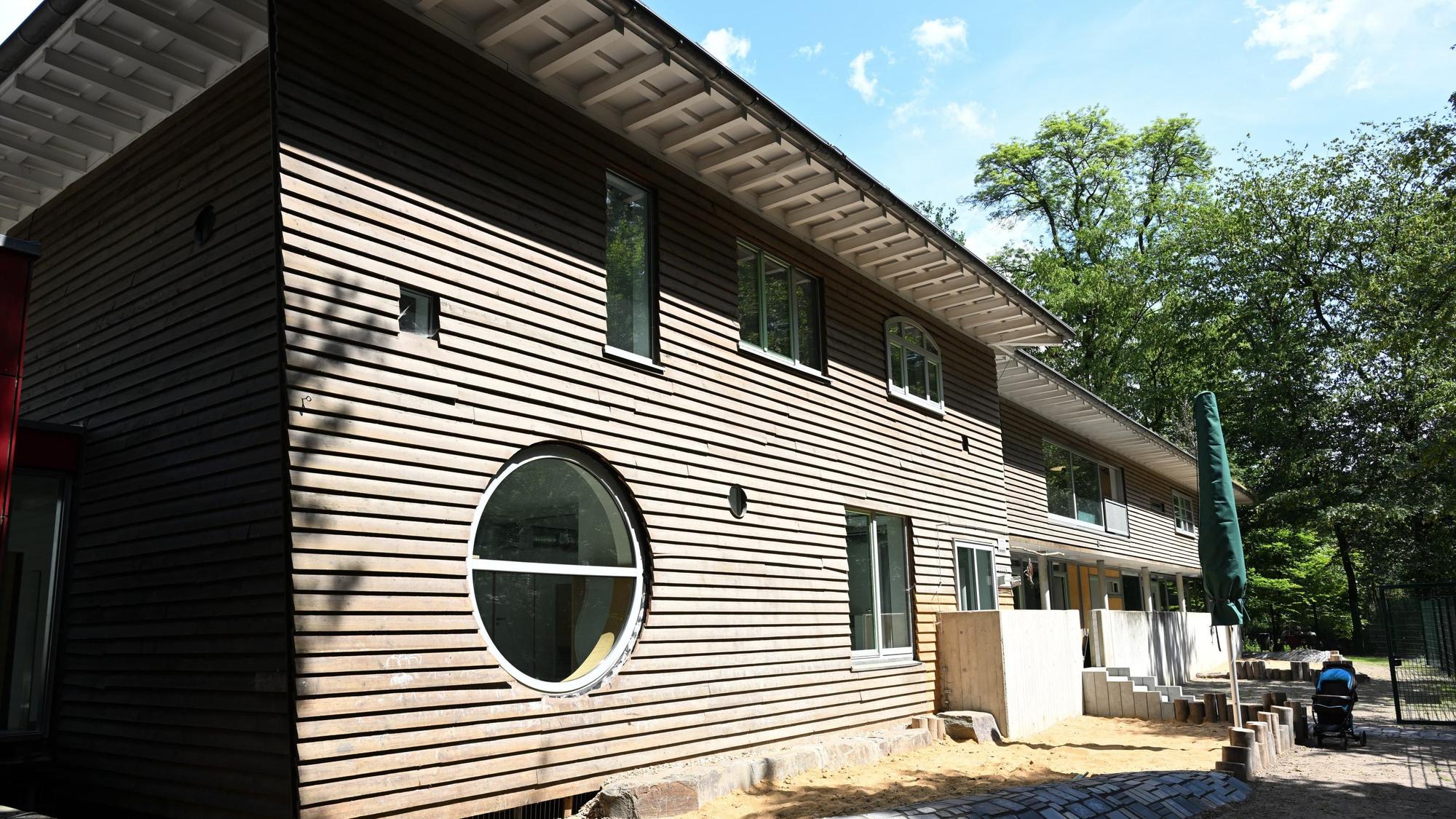 Ein moderner Holzbau mit begrüntem Dach. Davor noch eine sandige Baustelle.