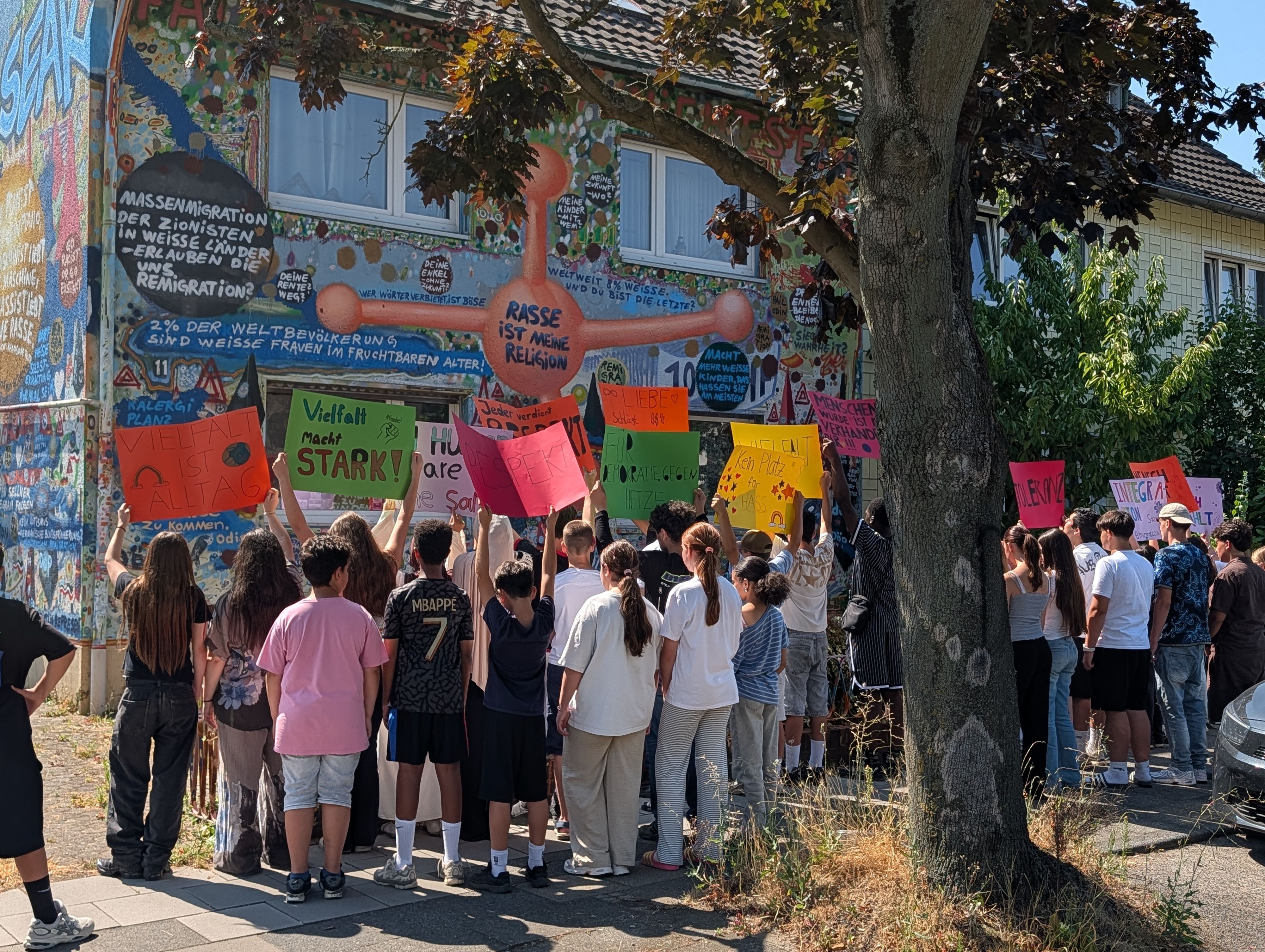 Das Foto zeigt Schülerinnen und Schüler mit Plakaten vor dem Wohnhaus des Künstlers.