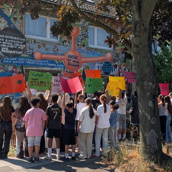 Das Foto zeigt Schülerinnen und Schüler mit Plakaten vor dem Wohnhaus des Künstlers.