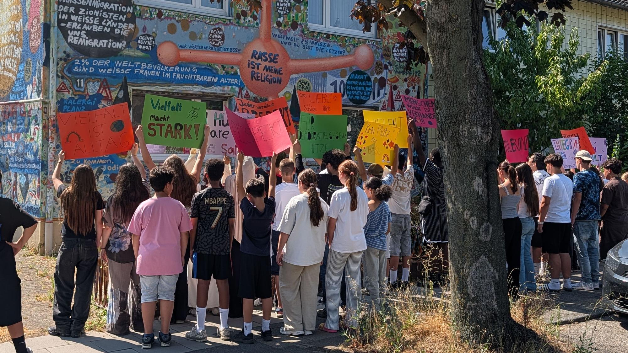 Das Foto zeigt Schülerinnen und Schüler mit Plakaten vor dem Wohnhaus des Künstlers.