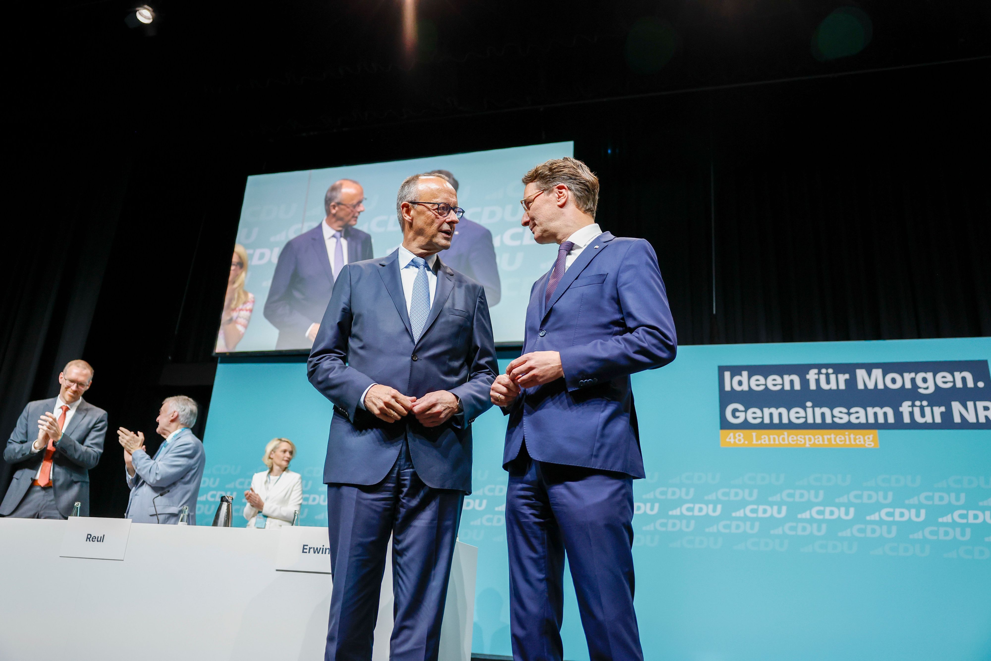 Bundeskanzler Friedrich Merz (l, CDU) steht beim Landesparteitag der CDU Nordrhein-Westfalen mit Hendrik Wüst (CDU), Ministerpräsident von Nordrhein-Westfalen, auf der Bühne.