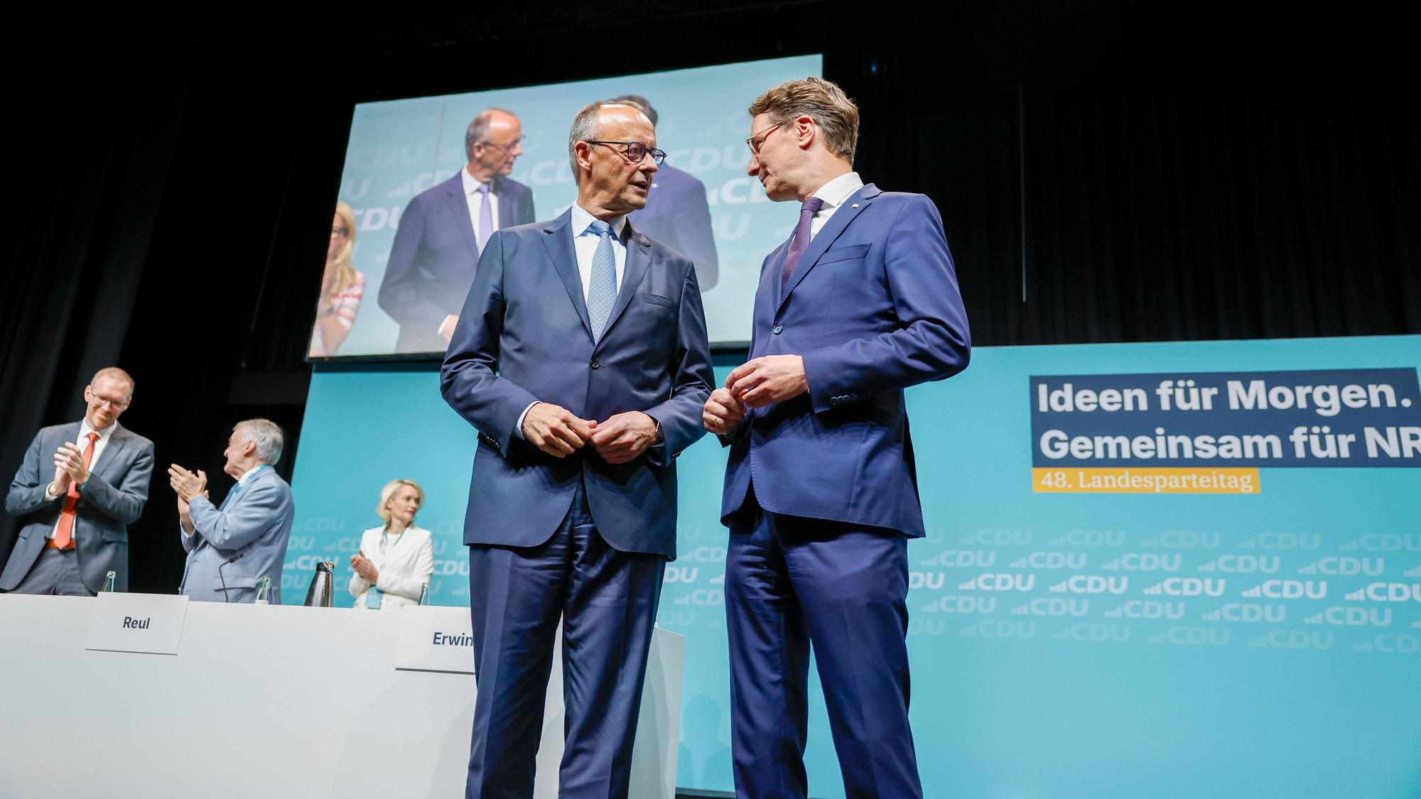 Bundeskanzler Friedrich Merz (l, CDU) steht beim Landesparteitag der CDU Nordrhein-Westfalen mit Hendrik Wüst (CDU), Ministerpräsident von Nordrhein-Westfalen, auf der Bühne.