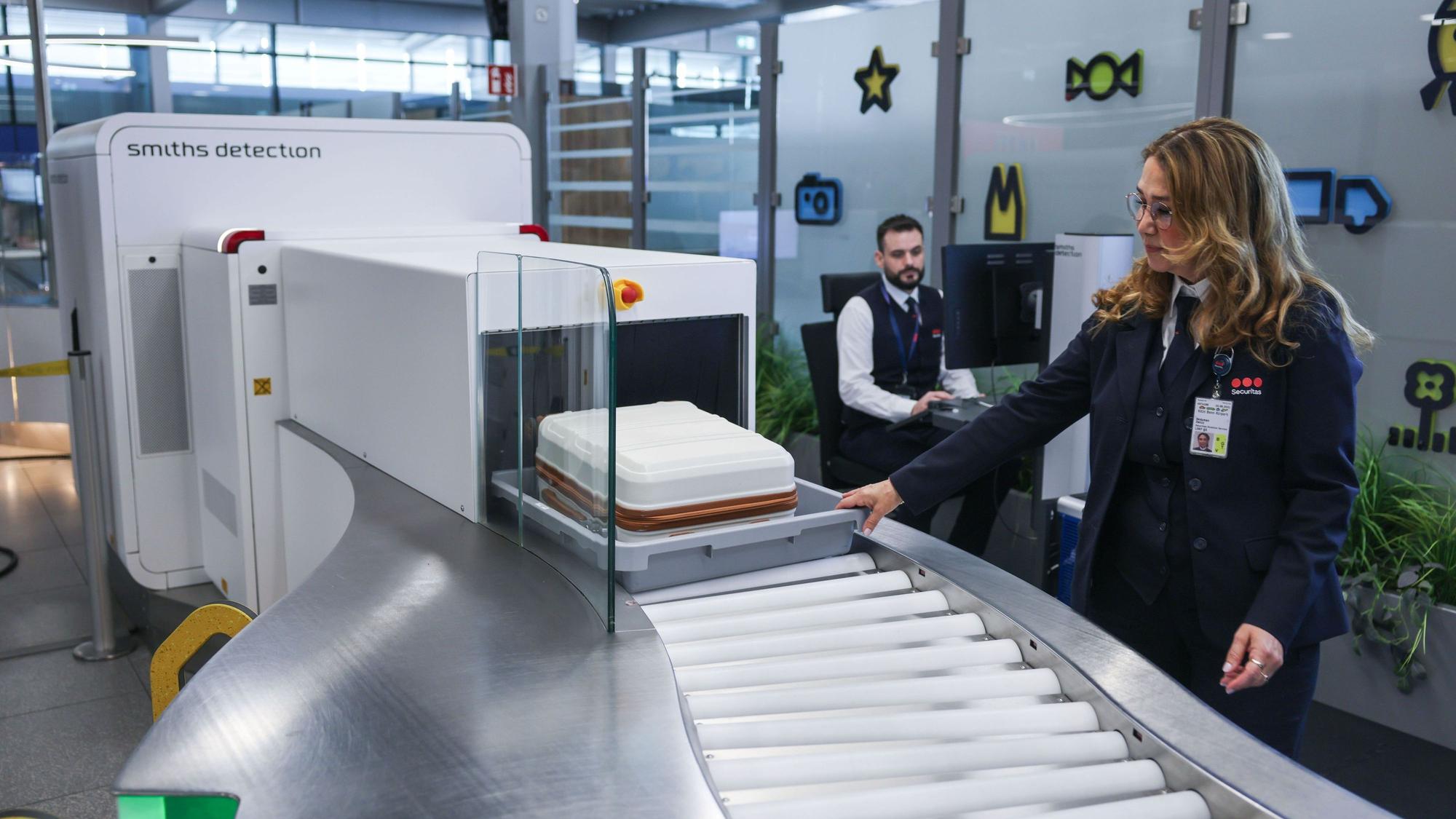 Die Mitarbeiterin einer Sicherheitsfirma schiebt im Sicherheitsbereich am Flughafen Köln/Bonn einen Koffer in einen Scanner. Eine neue Anlage mit elf modernen CT-Kontrollspuren und Scannern soll künftig für schnellere, komfortablere und effizientere Abläufe sorgen.