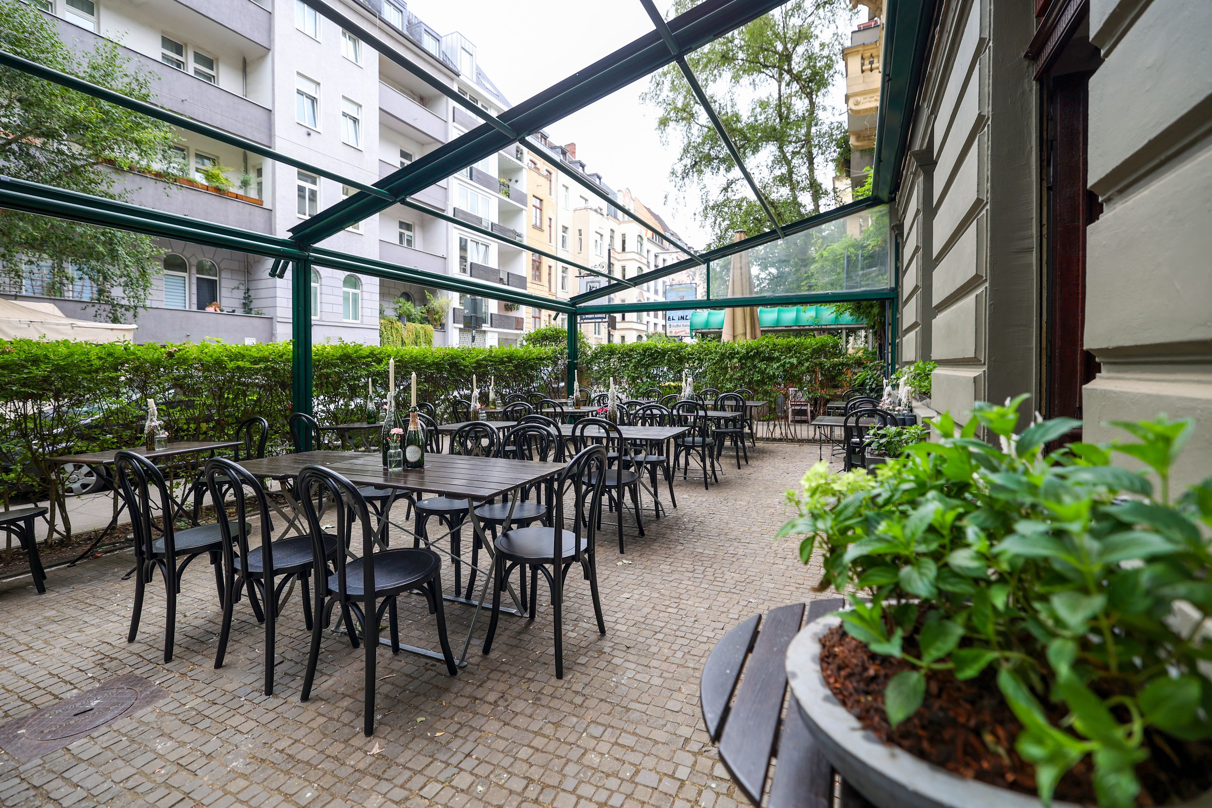 Die Terrasse in der Brasserie Santé mit dunklen Stühlen und Tischen.
