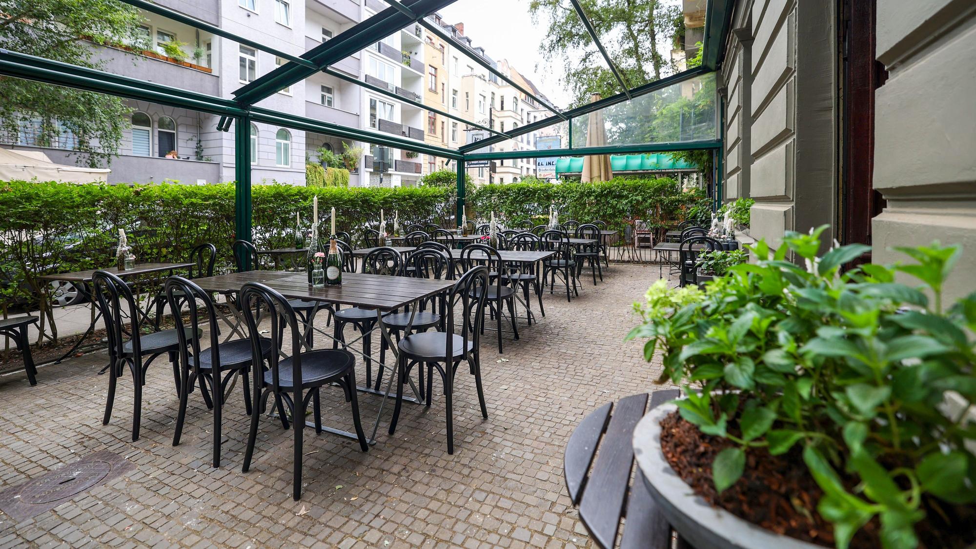 Die Terrasse in der Brasserie Santé mit dunklen Stühlen und Tischen.