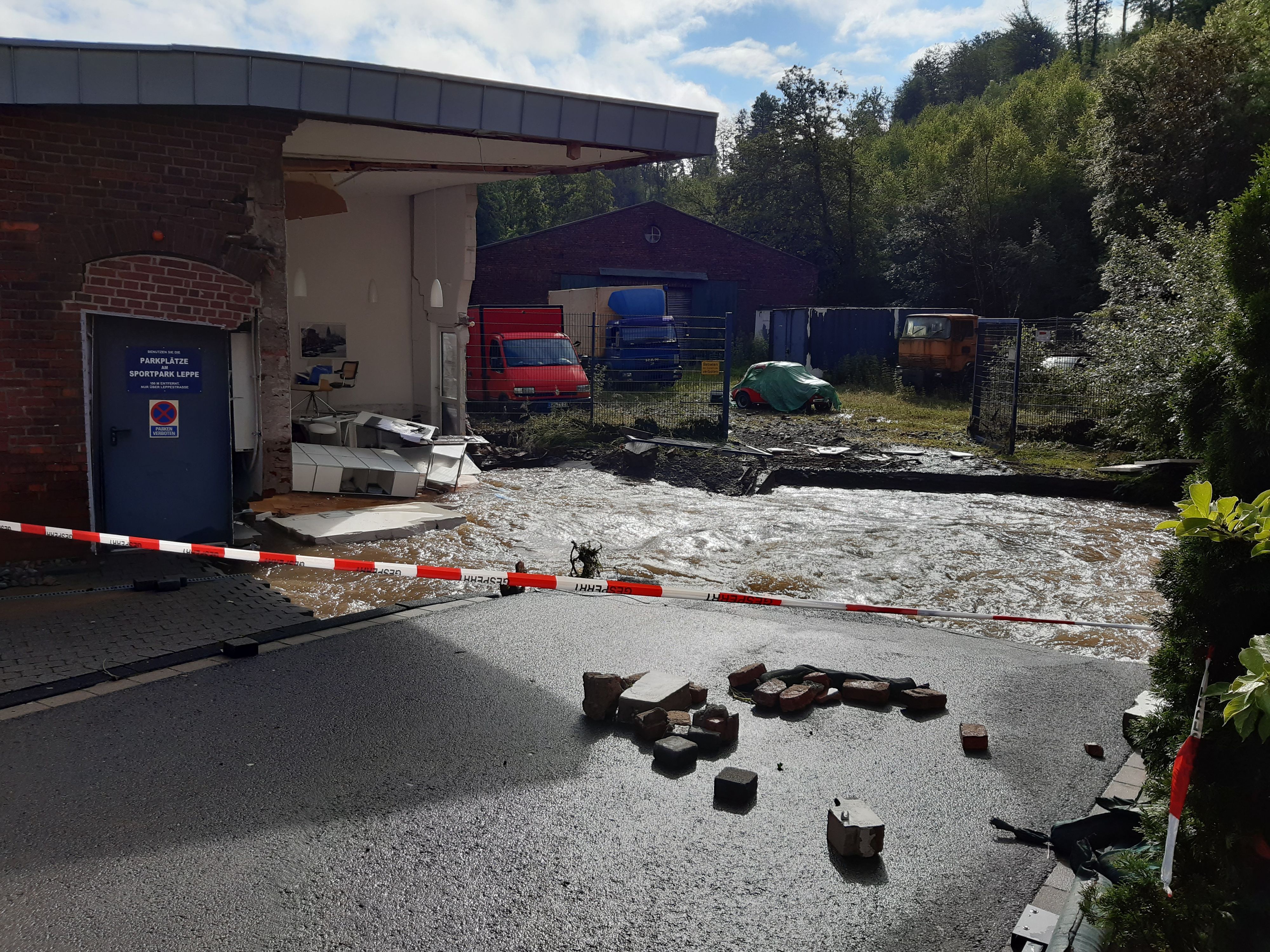 Ein Fluss fließt an einem zerstörten Haus vorbei.