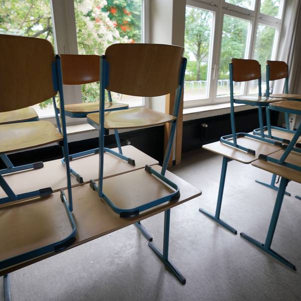 Stühle stehen in einem Klassenraum in einer Schule auf den Tischen.