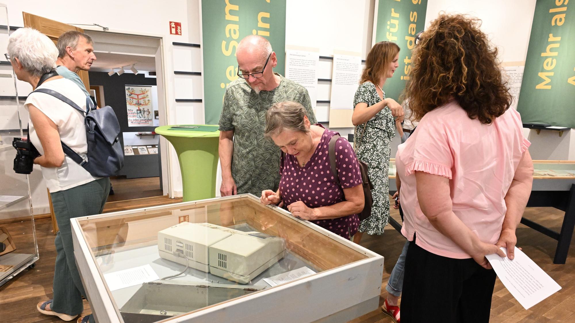 Gäste laufen durchs Museum und betrachten Objekte.
