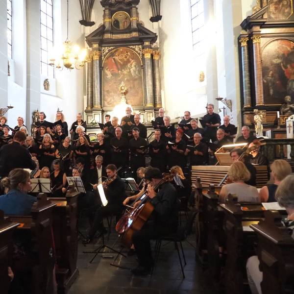 Im Vordergrund sitzen die Orchestermusiker, dahinter stehen die Chormitglieder.