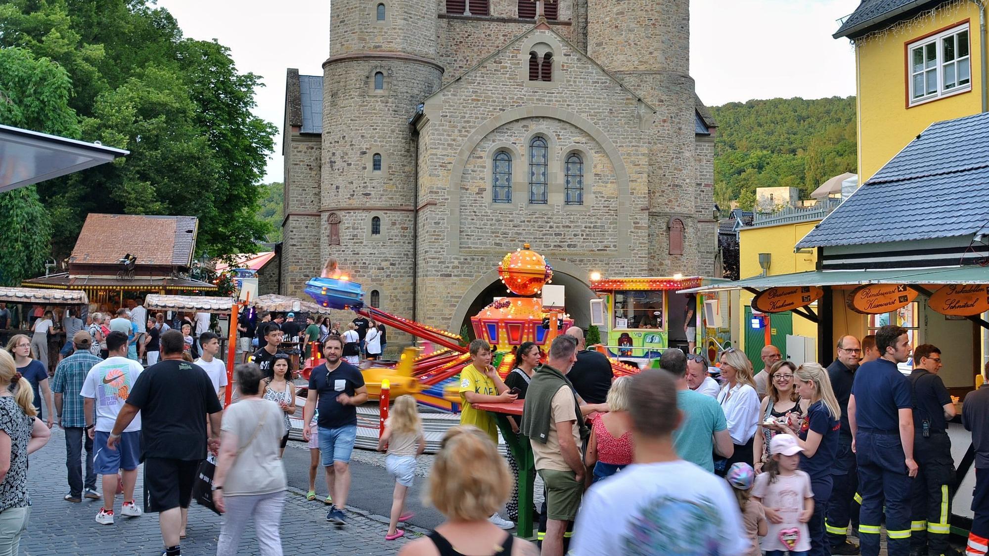 Ein Bild von der Kirmes im Sommer 2024. Menschen gehen über die Langenhecke, im Hintergrund ist die Stiftskirche zu sehen.