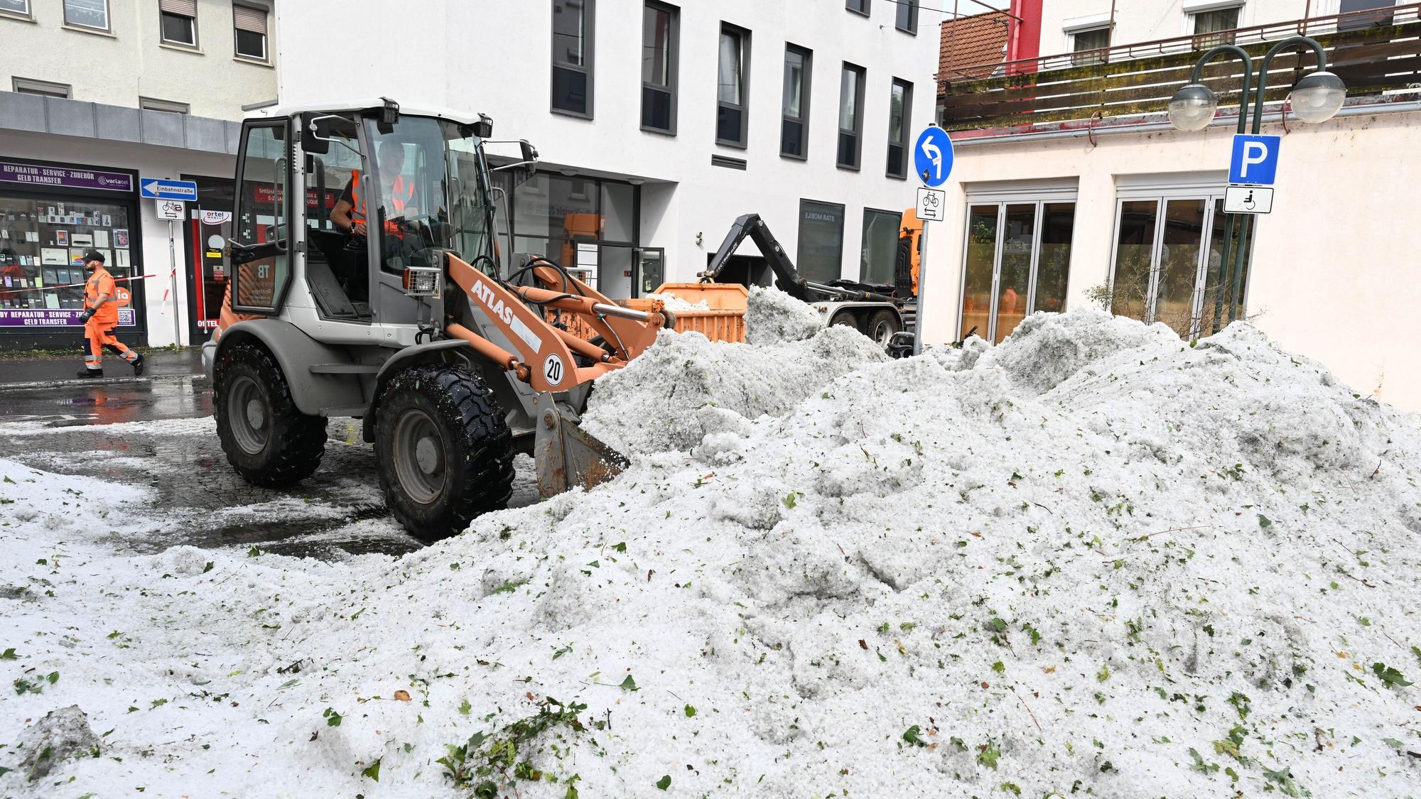 15.07.2026, Baden-Württemberg, Reutlingen: Mitarbeiter der Stadtreinigung entfernen Hagel, der nach einem Unwetter in der Innenstadt aufgetürmt wurde. (zu dpa: «Hagelsturm trifft Reutlingen - 6.000 Haushalte ohne Strom») Foto: Bernd Weißbrod/dpa +++ dpa-Bildfunk +++