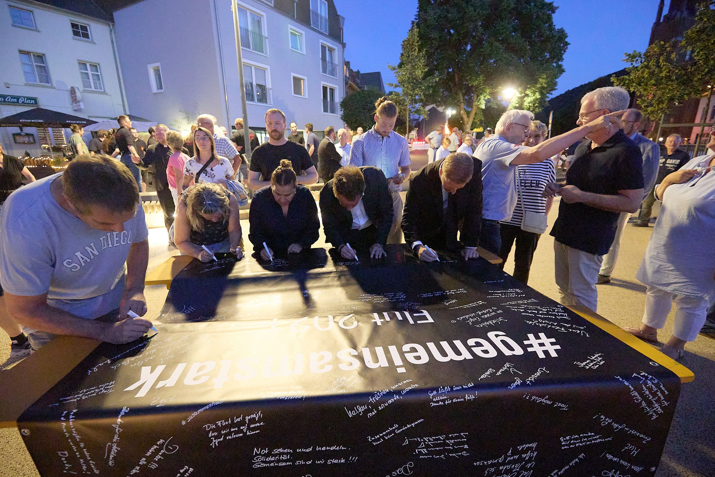Auf eine schwarze Plane schreiben die Menschen ihre Gedanken zur Flut.