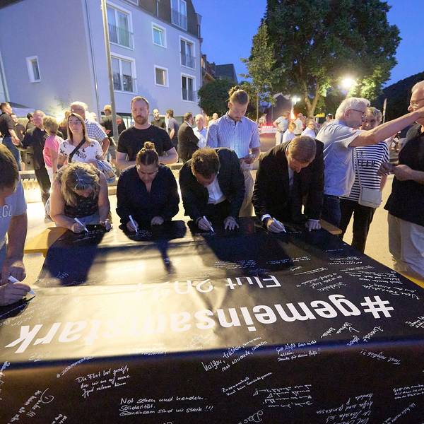 Auf eine schwarze Plane schreiben die Menschen ihre Gedanken zur Flut.