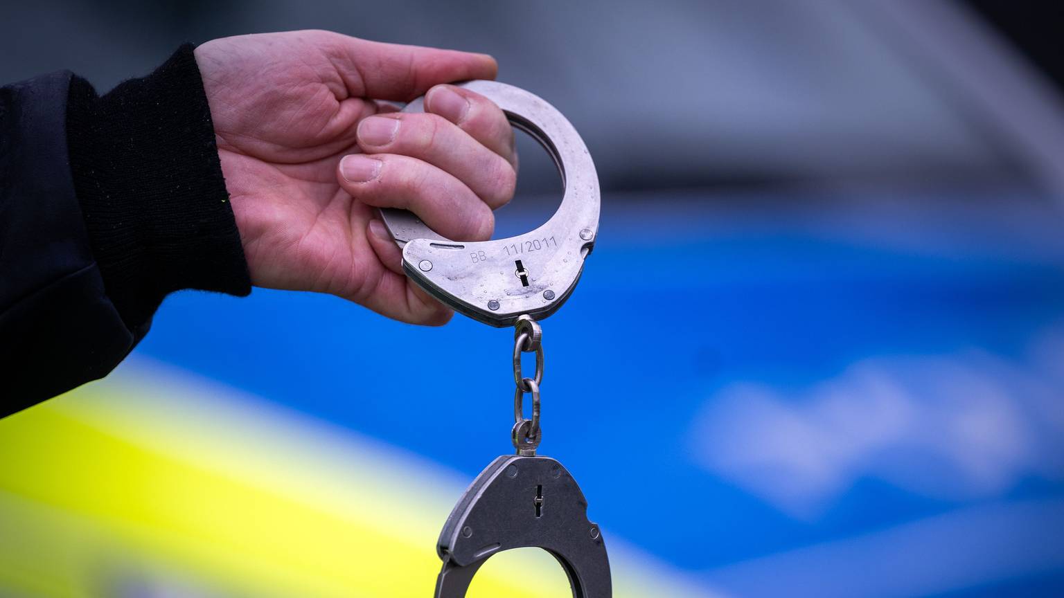 Ein Polizist hält Handschellen.