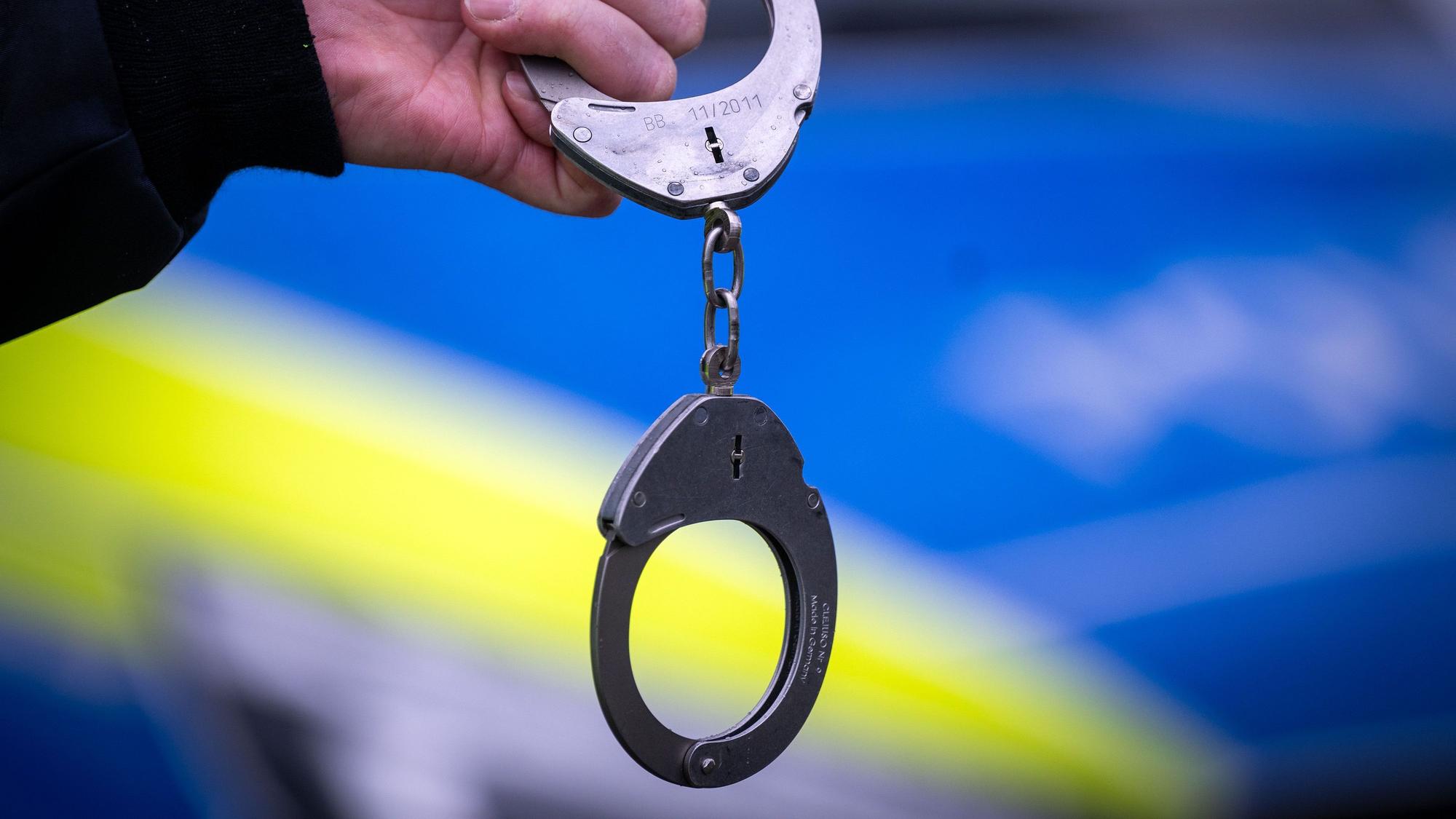 Ein Polizist hält Handschellen.