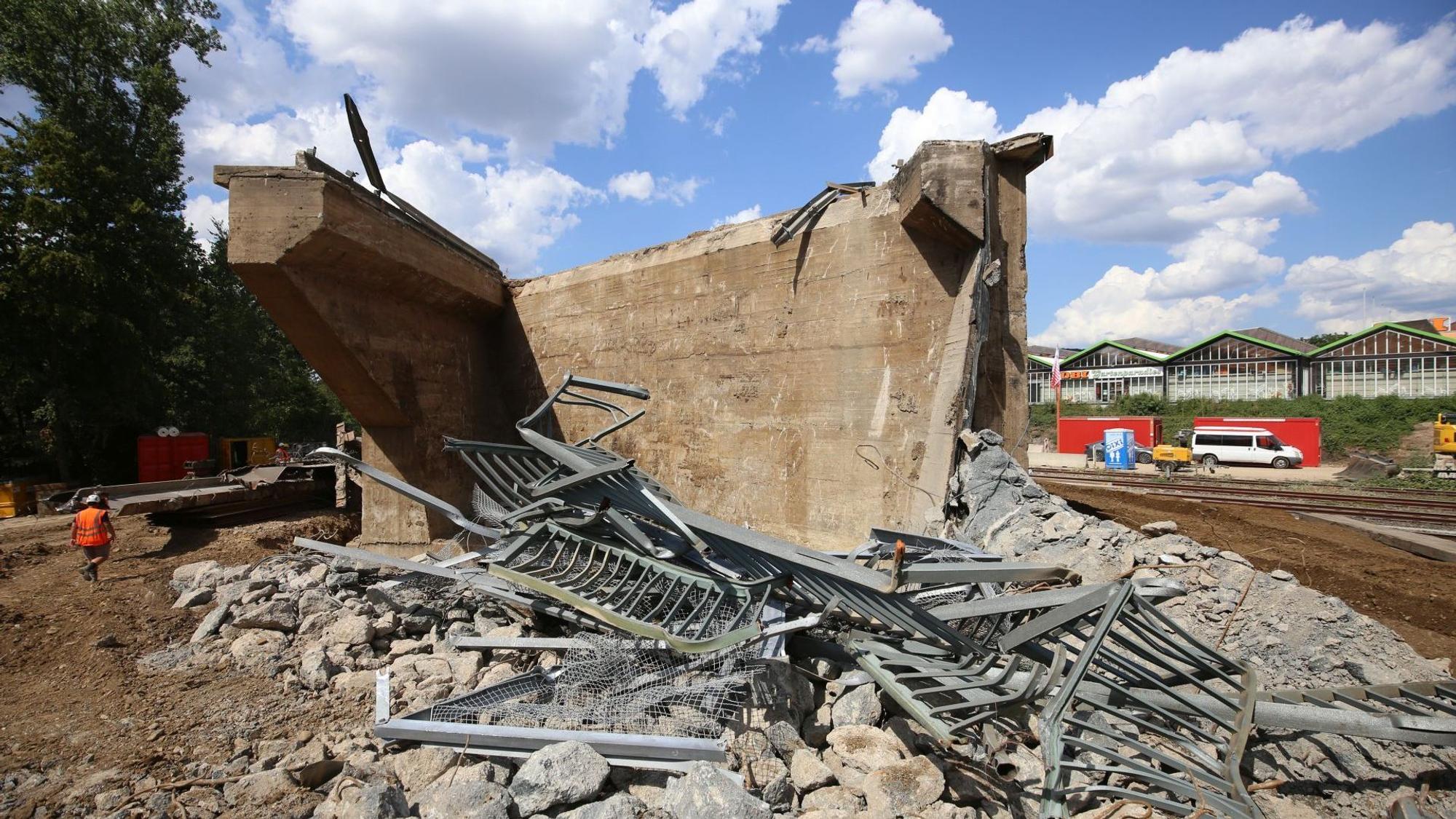 Ein Betonturm, davor verbogene Metallgeländer.