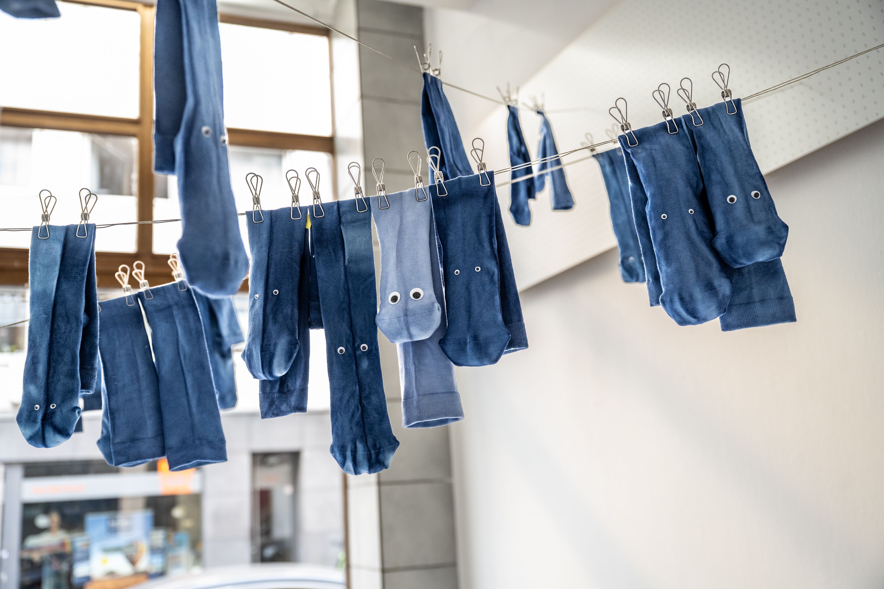 Blaue Socken mit Kulleraugen hängen an einer Leine