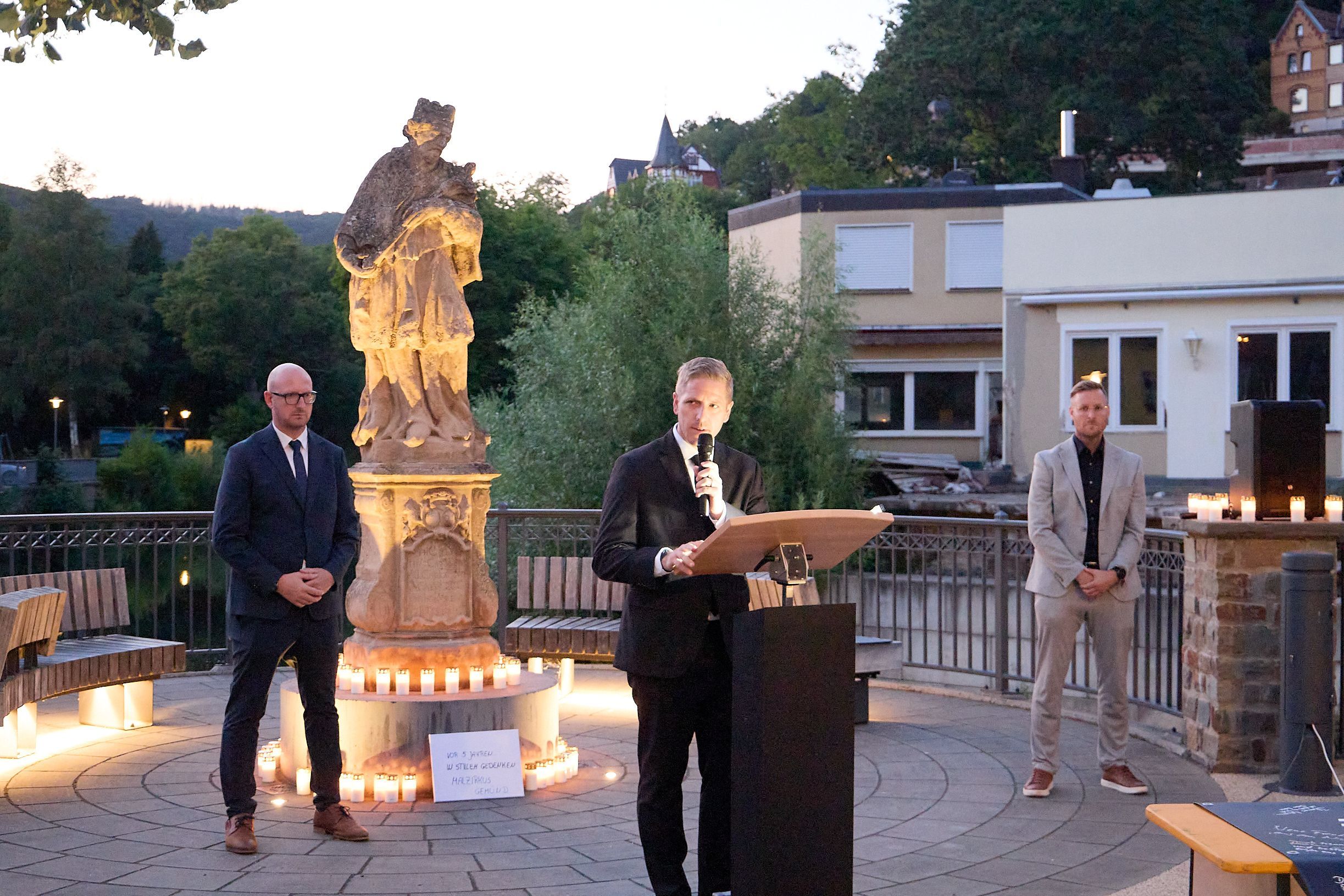 Landrat Markus Ramers spricht in Gemünd an der Nepomuk-Statue zu den Gästen, neben ihm die beiden Bürgermeister Ingo Pfennings und Martin Berners.