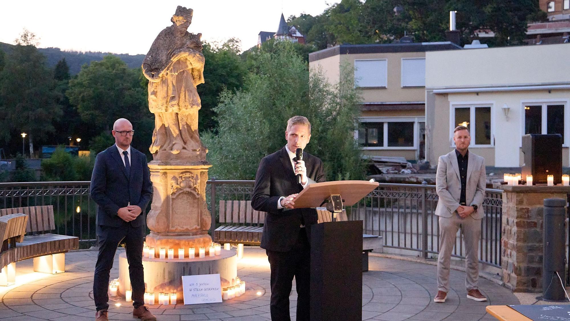 Landrat Markus Ramers spricht in Gemünd an der Nepomuk-Statue zu den Gästen, neben ihm die beiden Bürgermeister Ingo Pfennings und Martin Berners.