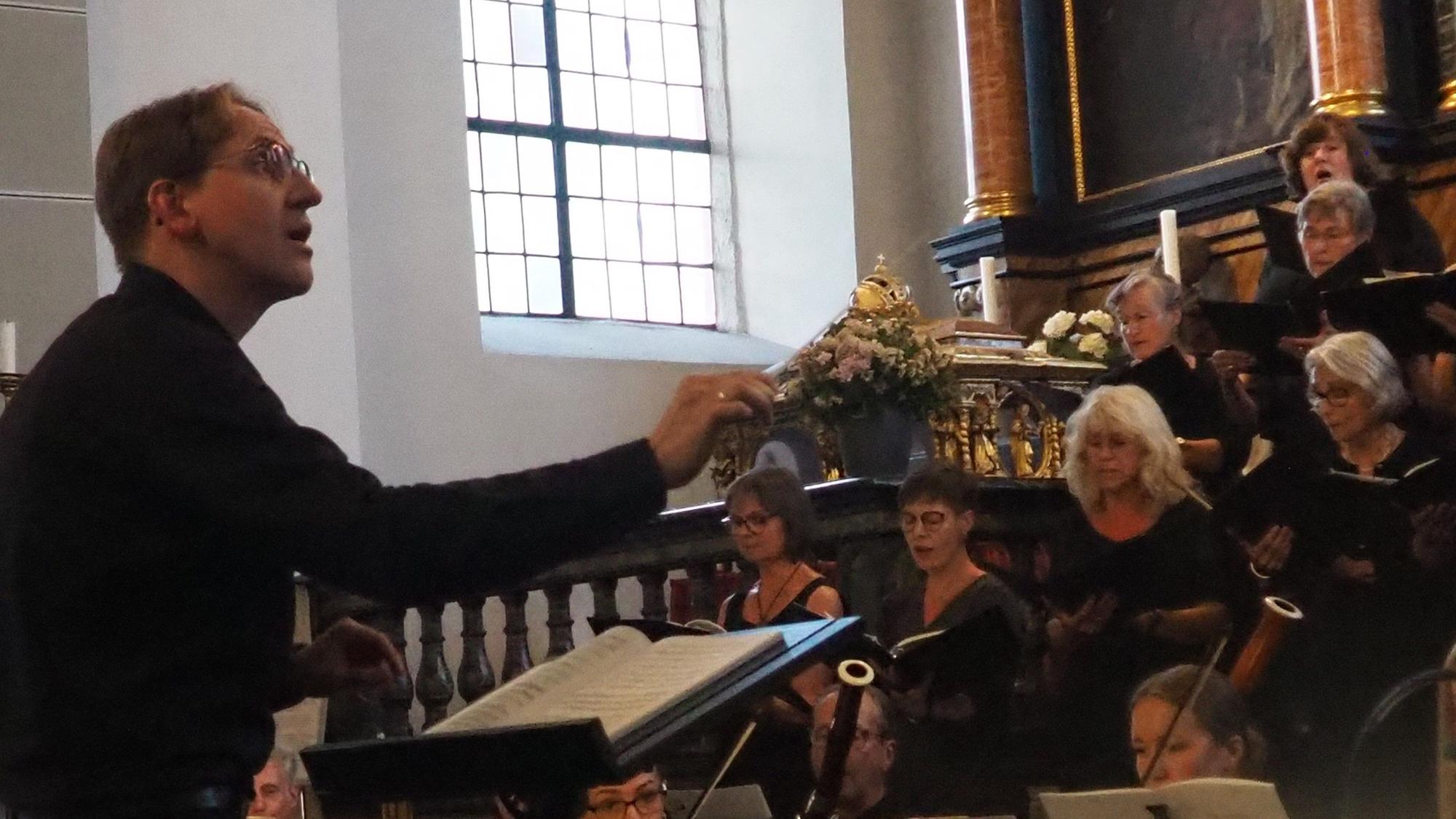 Andreas Schramek ist von der Seite zu sehen, wie er dirigiert.