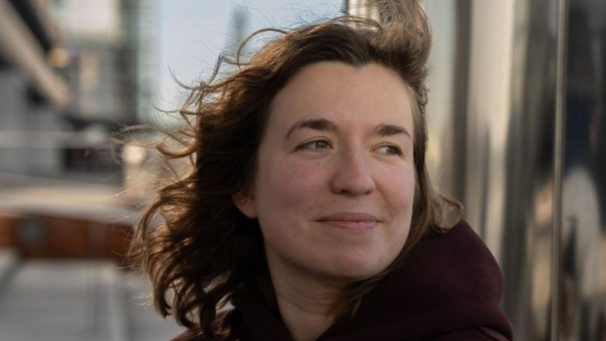 Das Foto zeigt eine Frau, durch ihre Haare streicht der Wind.
