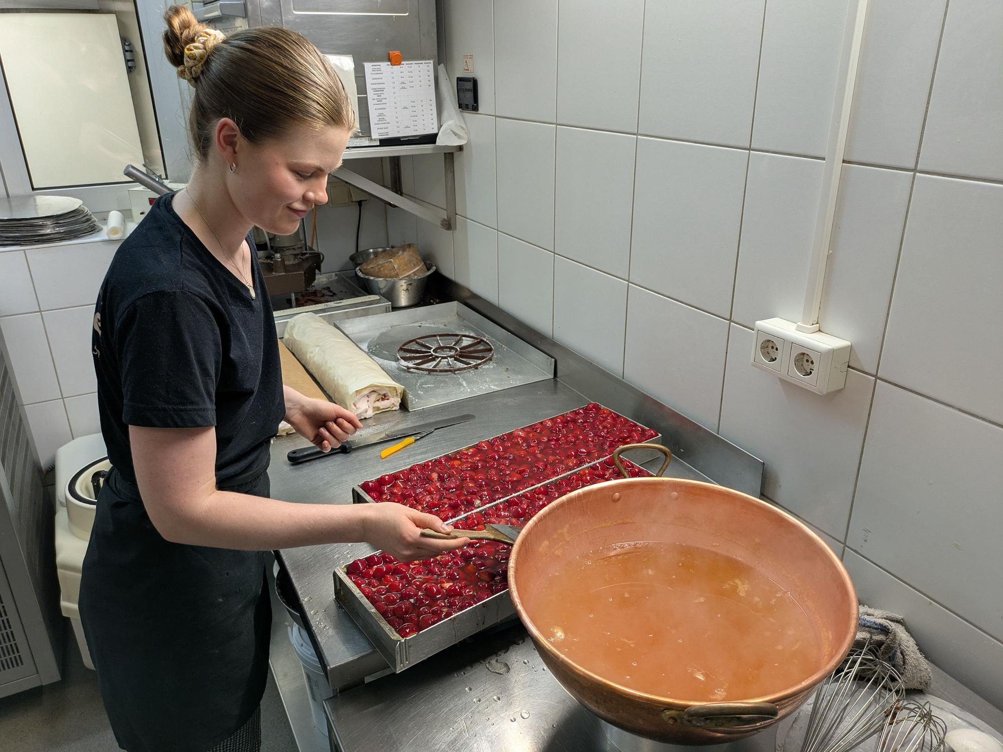 Isabelle Willeke streicht Tortenguss auf Erdbeerkuchen.